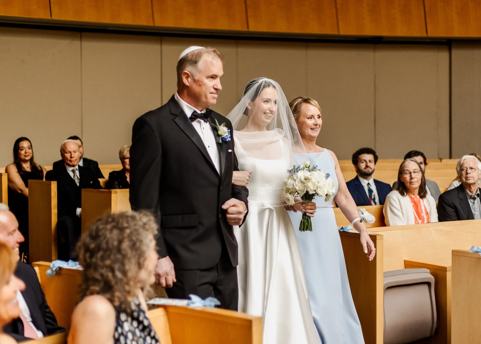 Sarah walking down the sactuary aisle during ceremony in the Temple Shir Shalom sanctuary