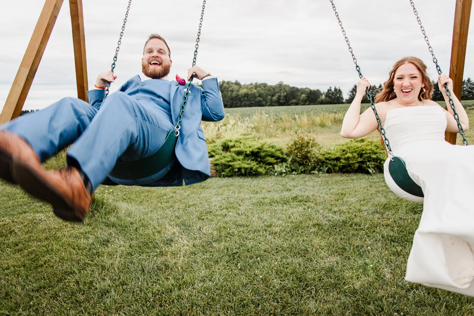 action shot of bride and groom on swings in front of a corn field at bloom and bower in rising sun ohio