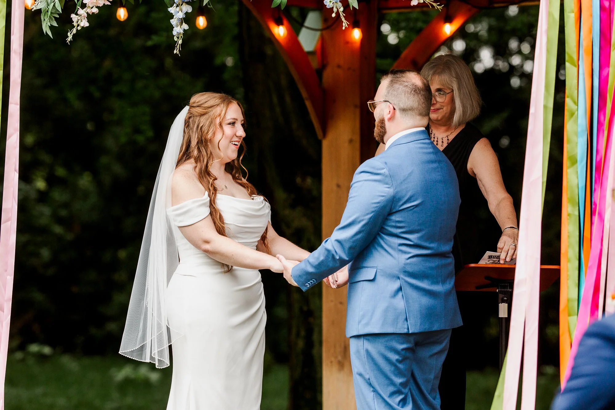 close up of bride and groom holding hands and facing each other at the alter during ceremony