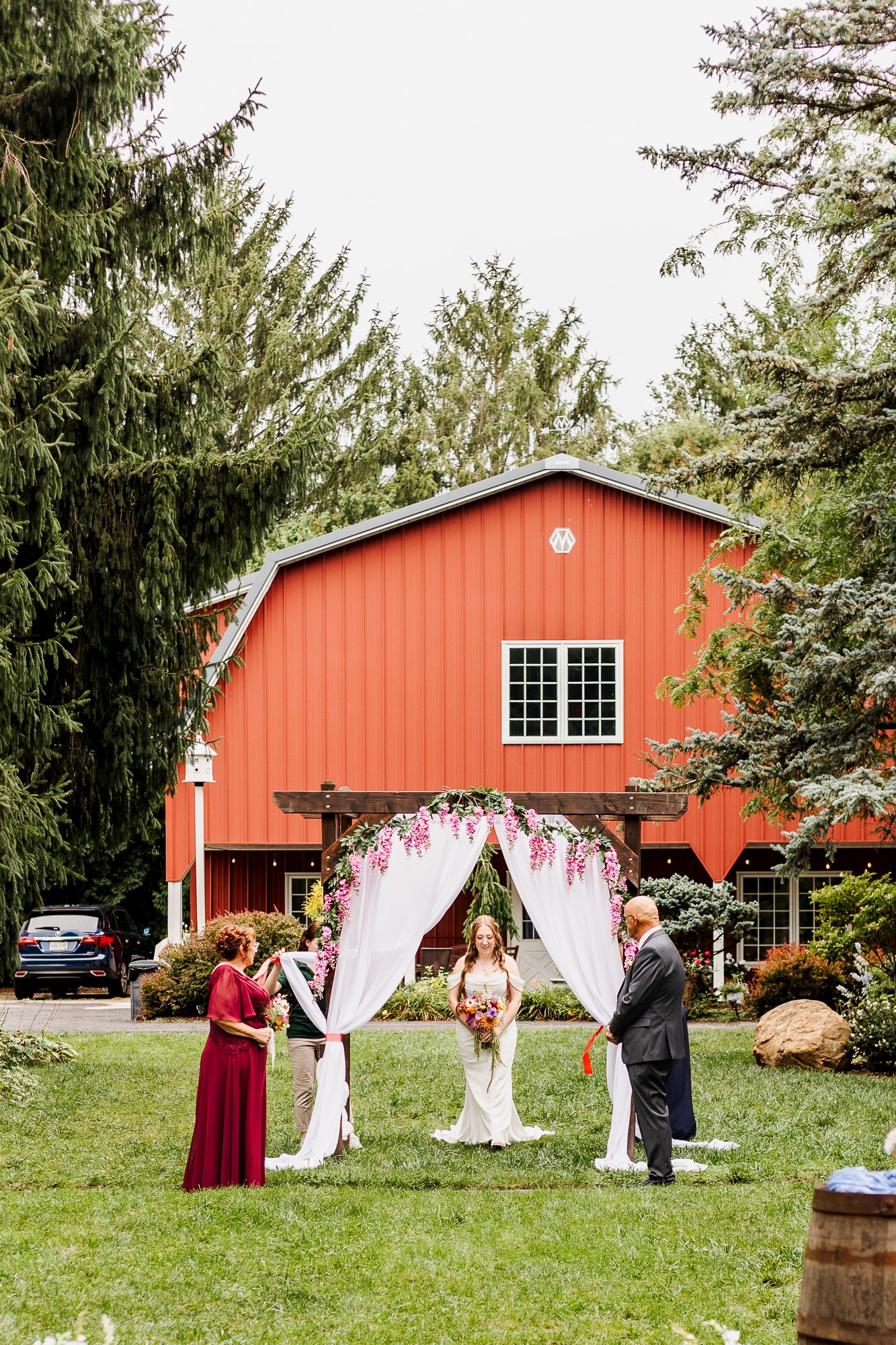 Bride enters wedding ceremony under archway that has white curtains pulled back at bloom and bower in rising sun ohio