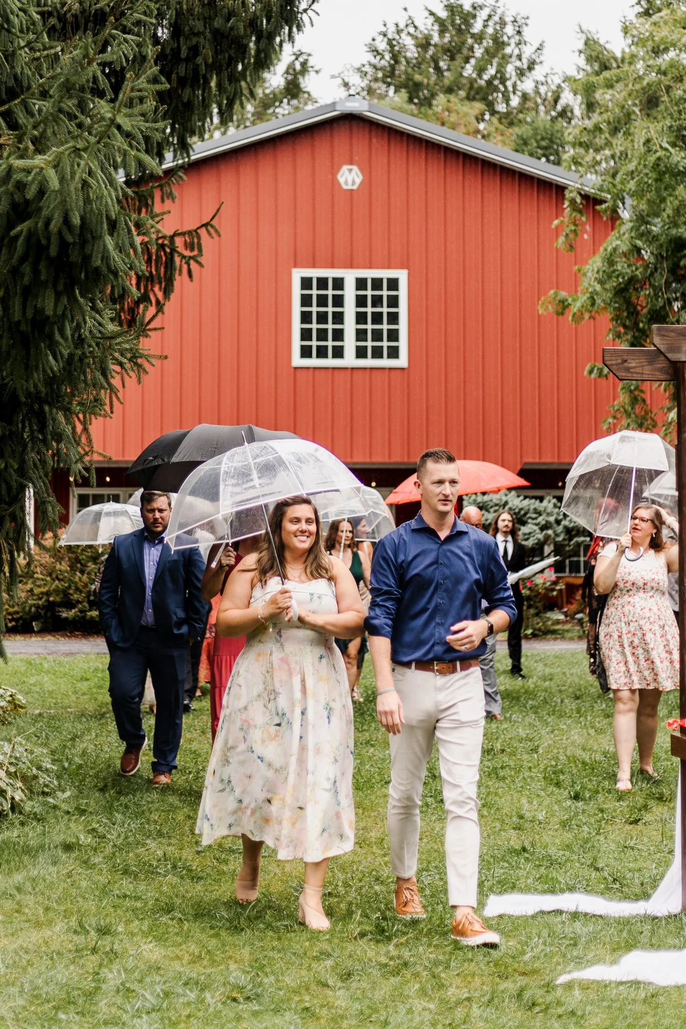 Guests carrying umbrellas while they arrive at the cermony site on the lawn of bloom and bower in rising sun ohio