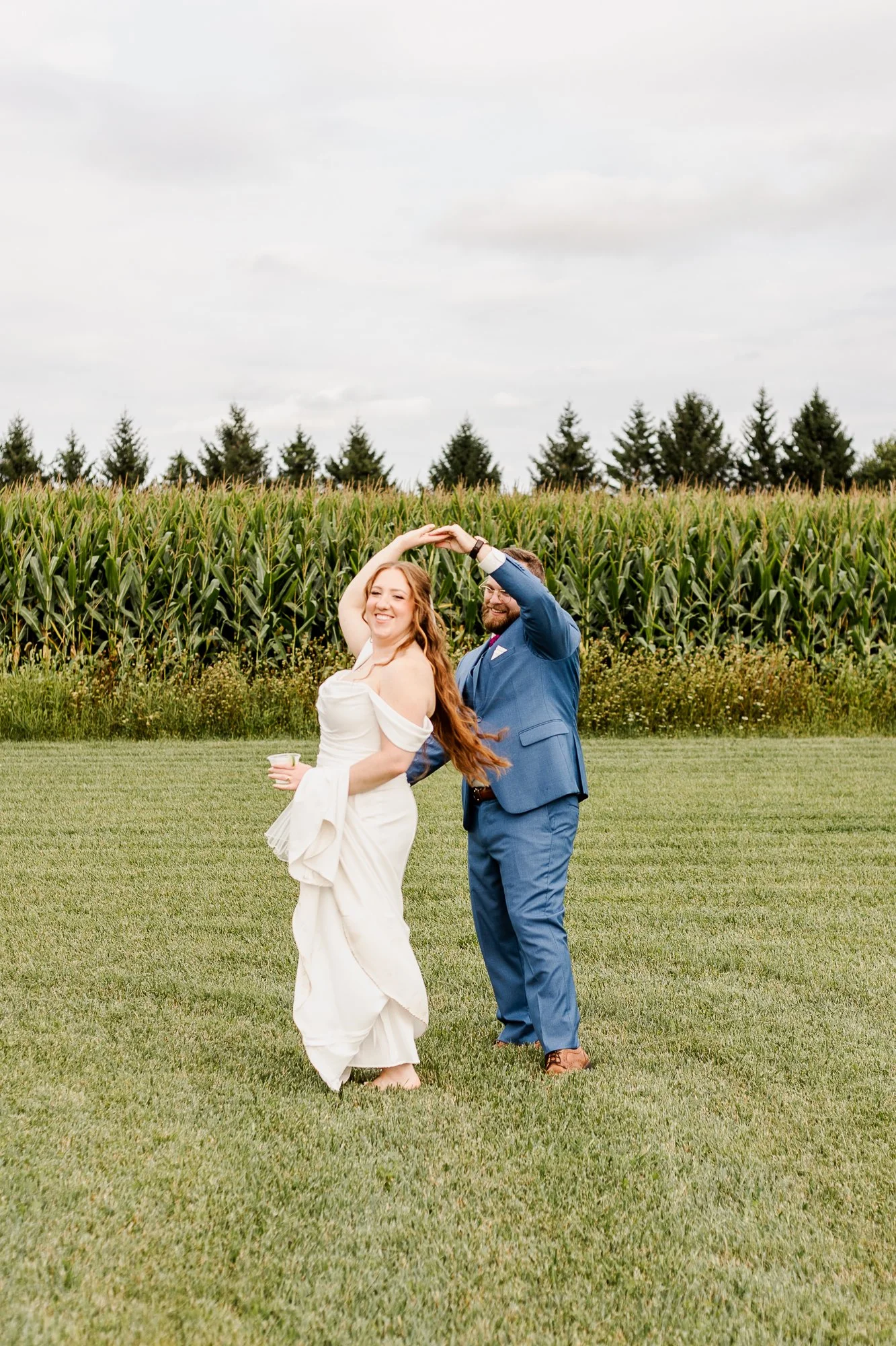 full length shot of groom twirling bride around in front of the corn field at bloom and bower in rising sun ohio