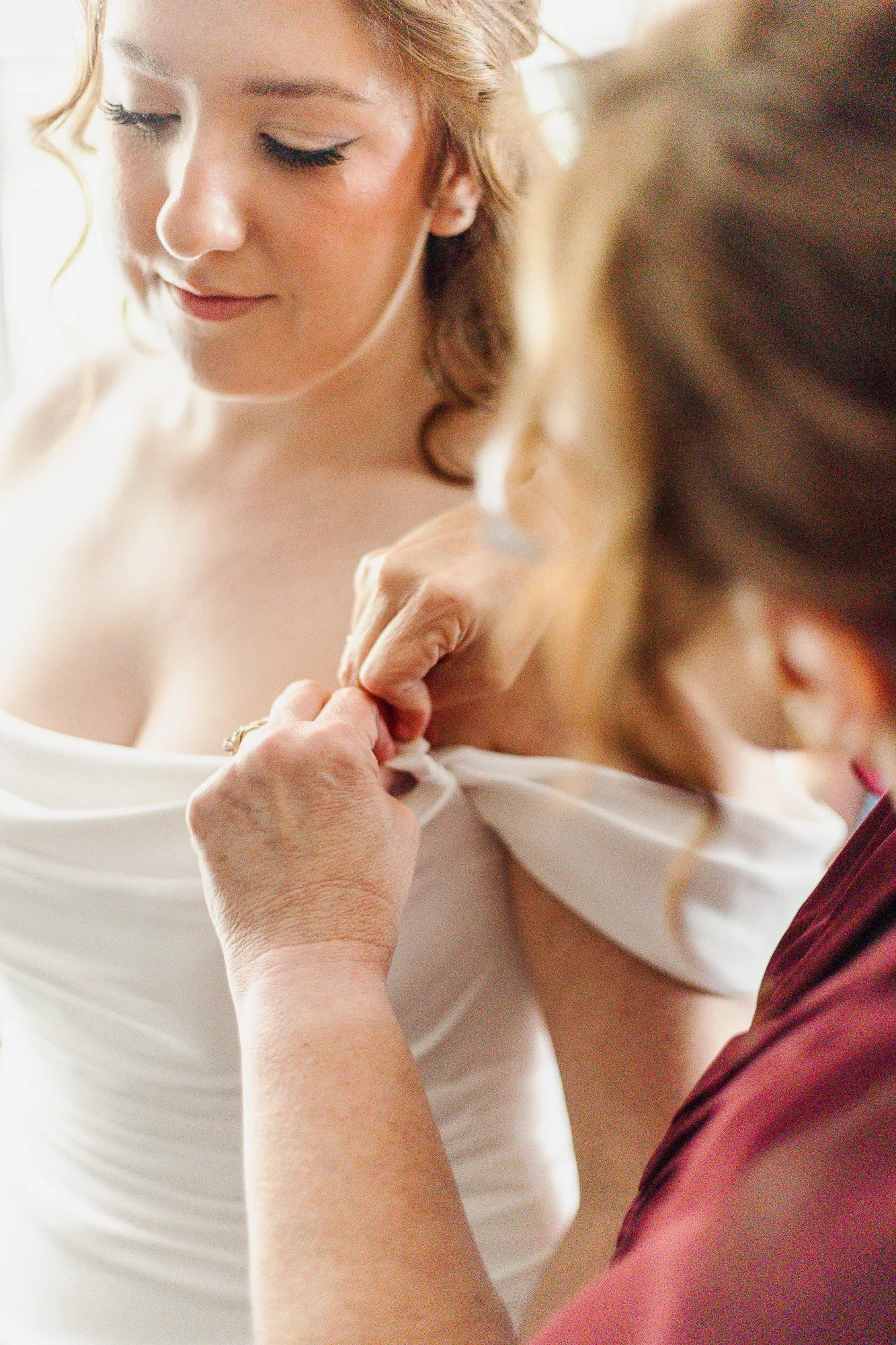 Mother of the bride helping bride clasp sleeves on dress at Bloom and Bower in Risingsun, Ohio