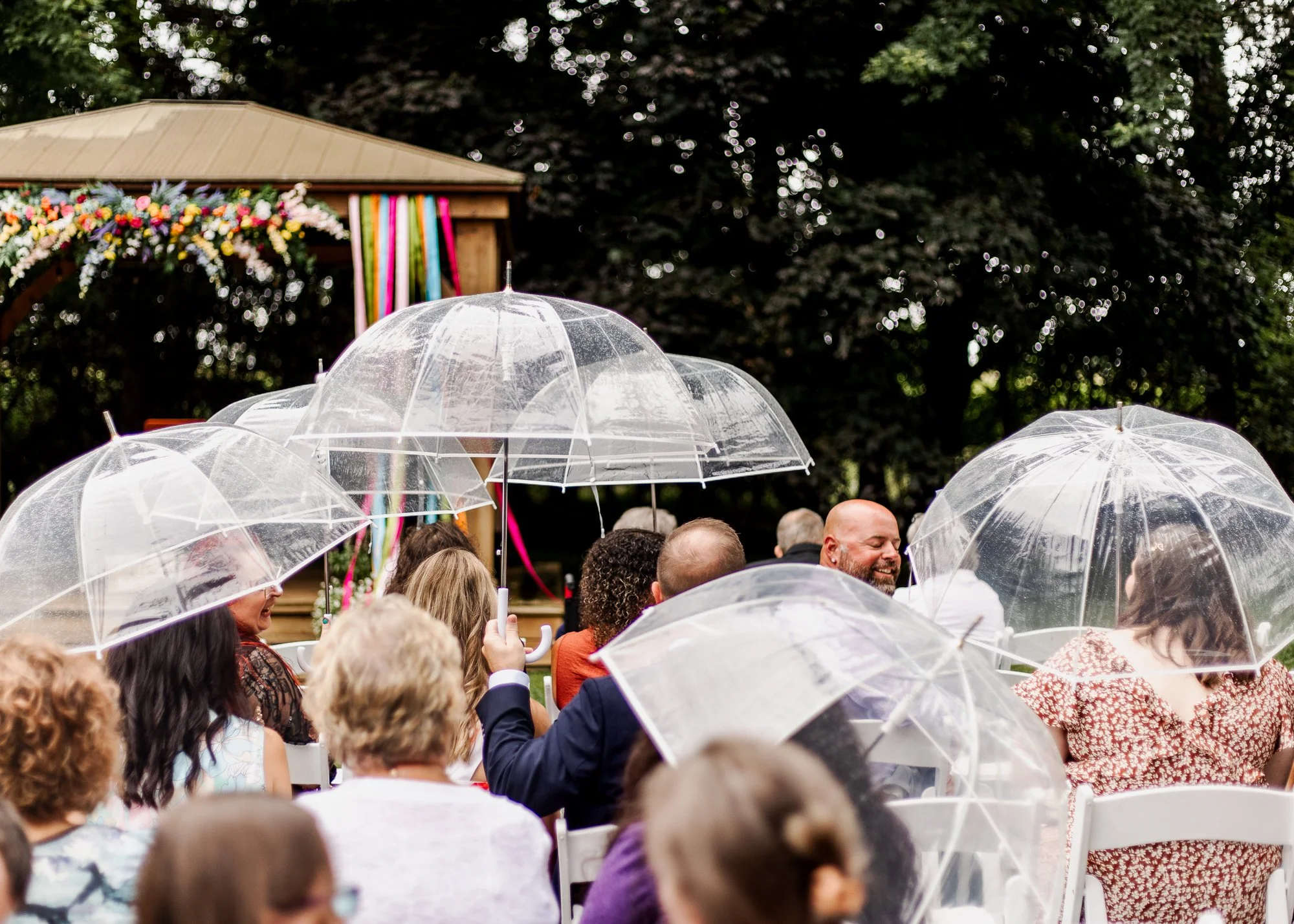 Guests carrying umbrellas while they wait at the ceremony site at bloom and bower in rising sun ohio