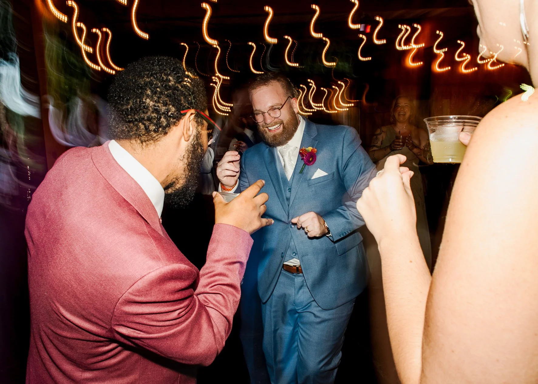 groom dancing with guests on a dark dance floor during wedding reception