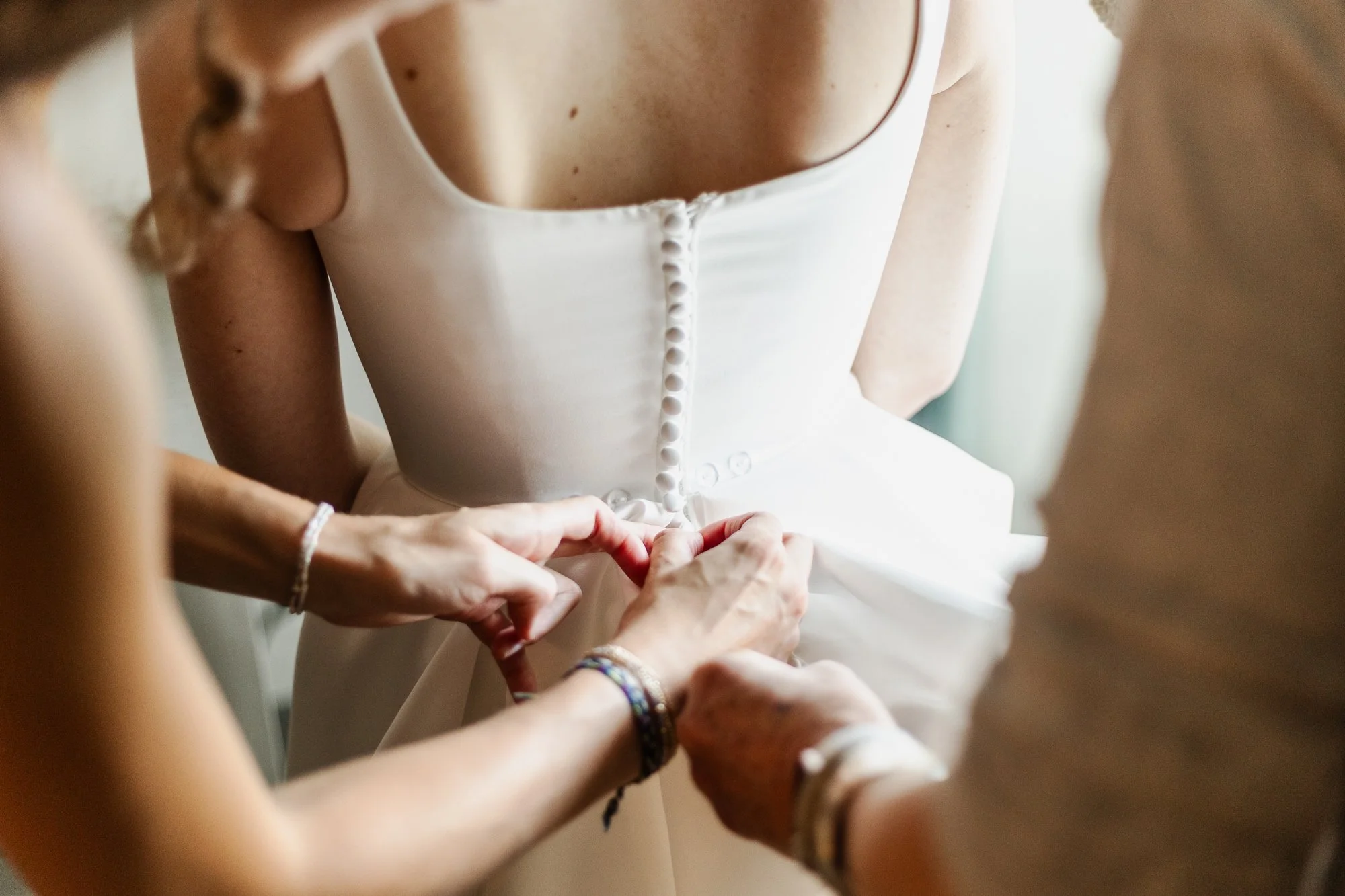 Sarah buttoning her wedding dress at The Kingsley