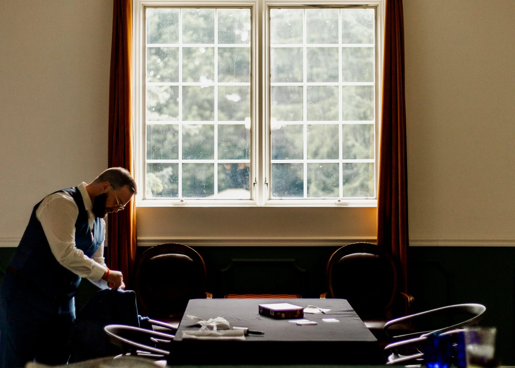 Groom getting ready in a window lit room at Bloom and Bower in Risingsun, Ohio