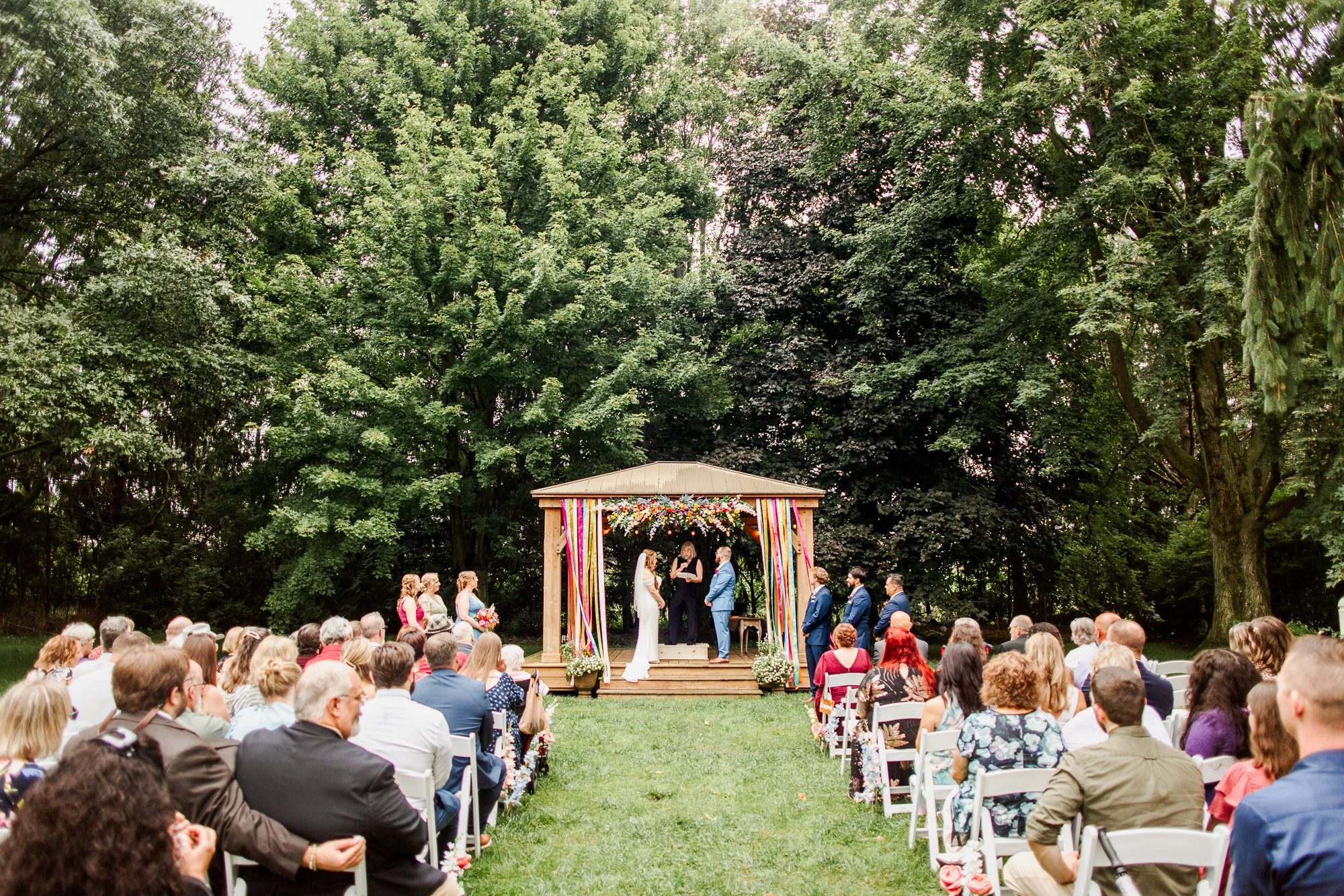 wide shot of bride and groom holding hands and facing each other at the alter during ceremony