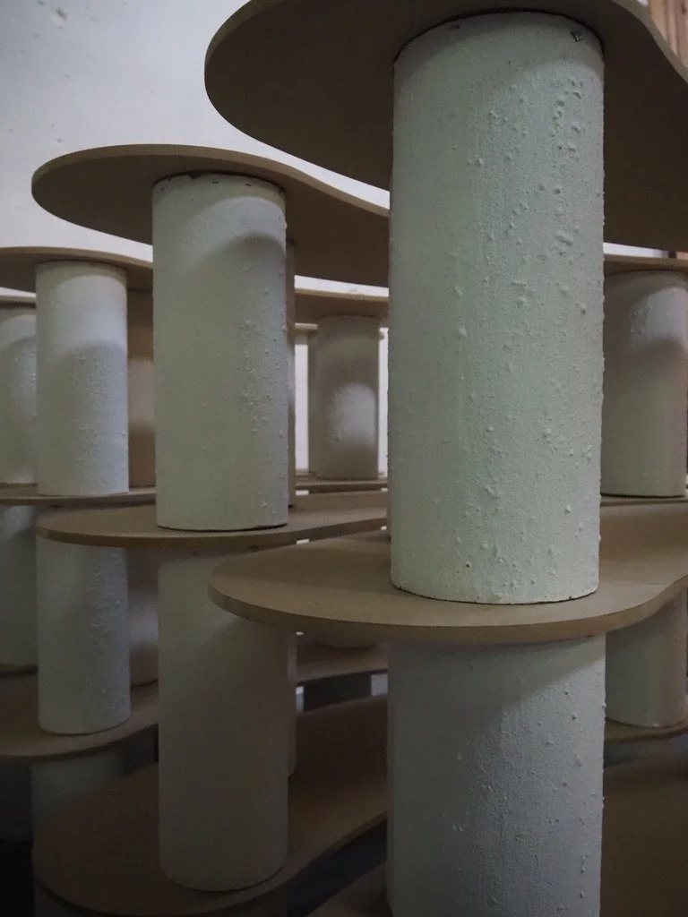 Stacked cardboard spools or supports with a round top and cylindrical base, arranged in layers.
