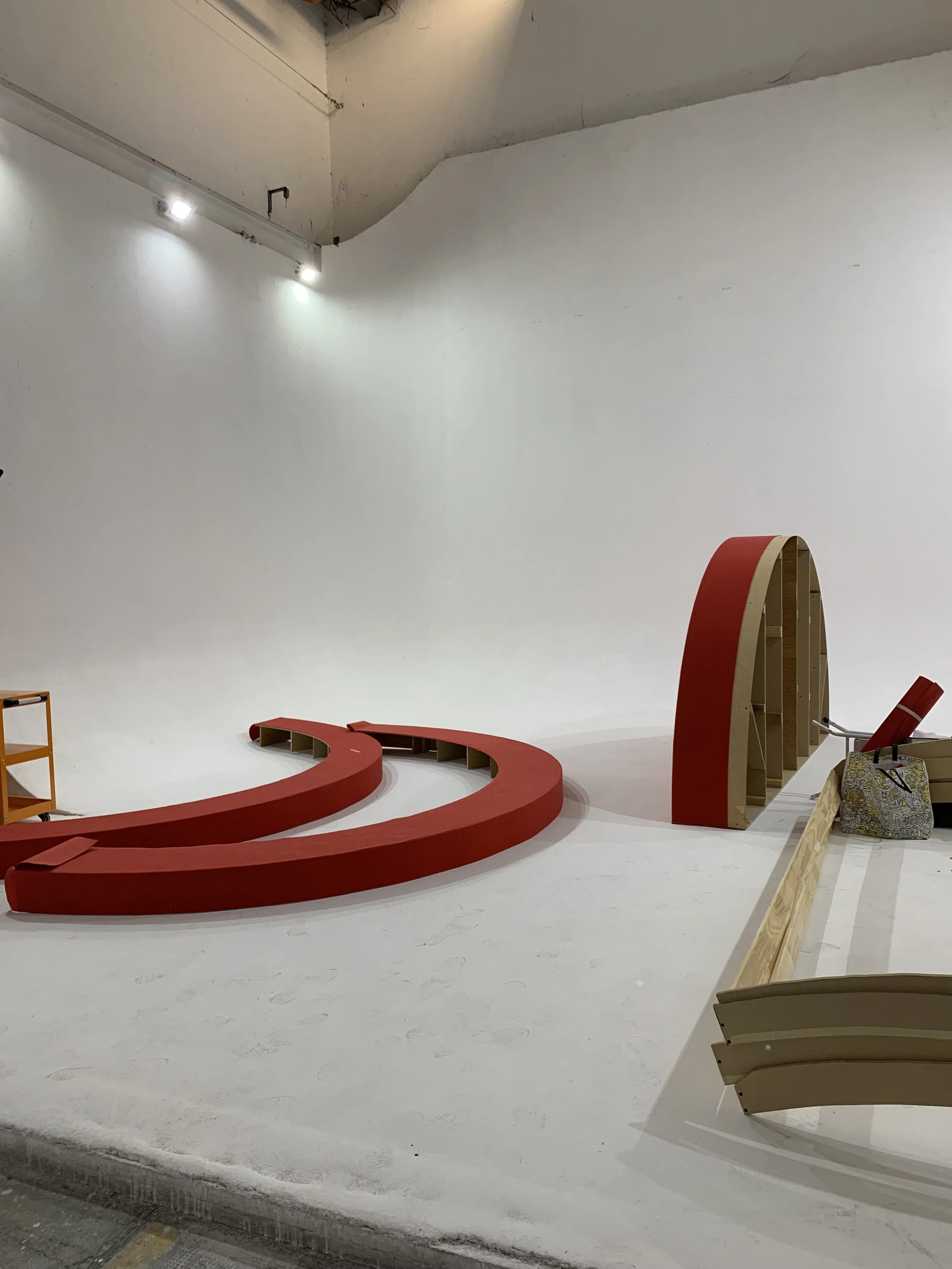 Construction site with a large red letter 'Q' and an arch structure inside a white room.