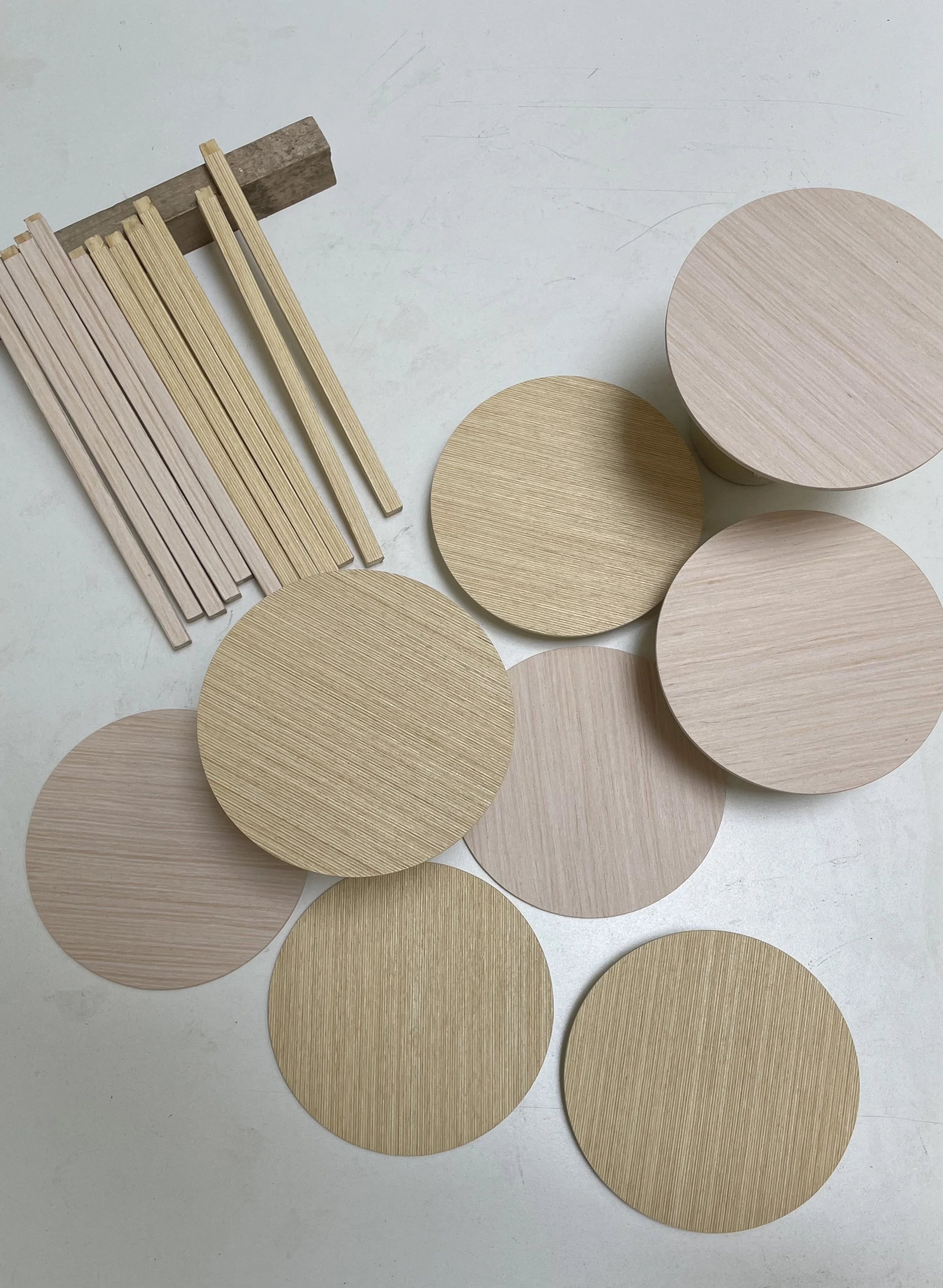 Various wooden circular and rectangular objects, and long thin wooden sticks on a light surface.