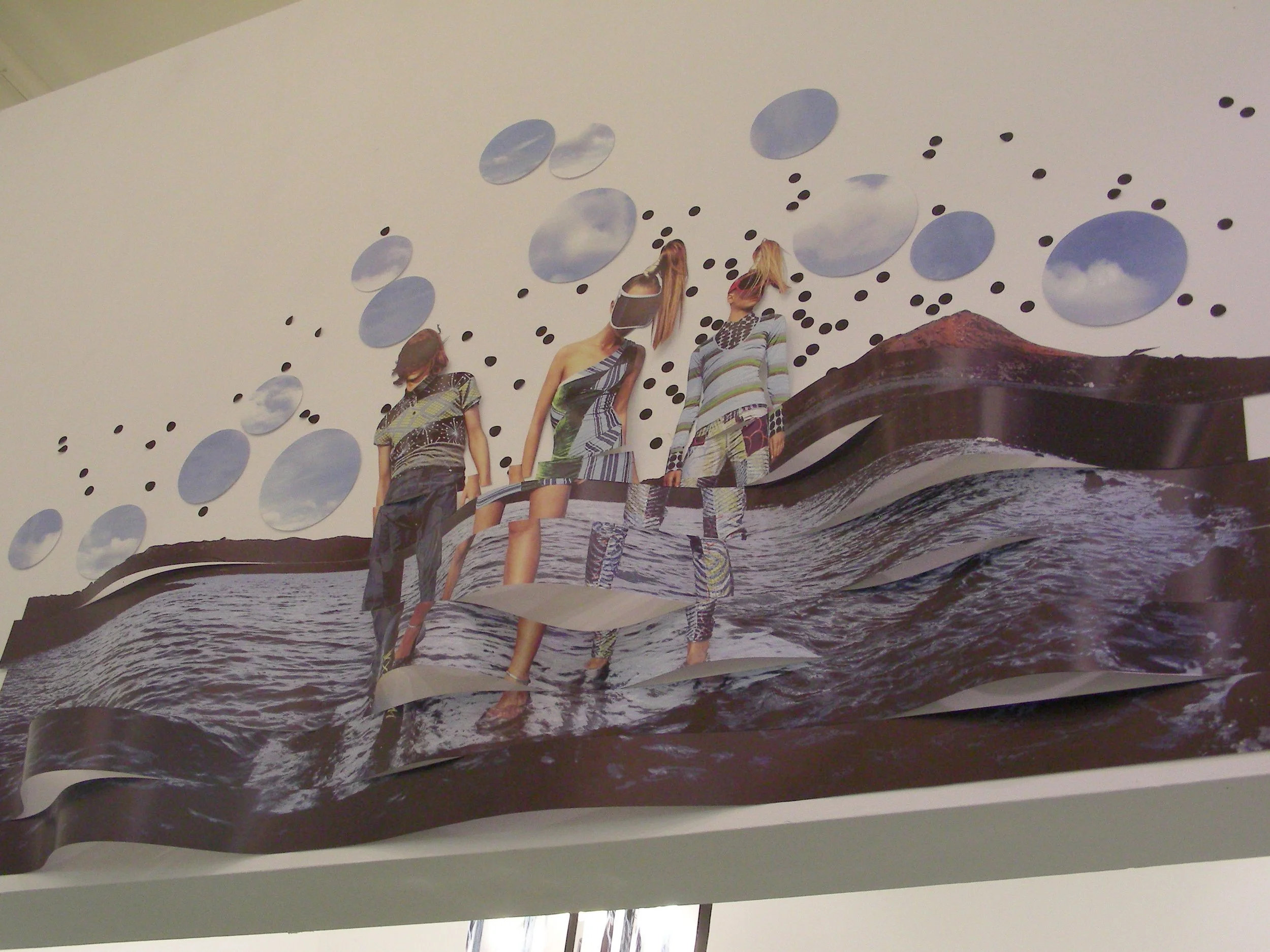 A wall art piece featuring three fashionably dressed women standing on a beach with a wavy pattern, and sky-themed circular cutouts above them.