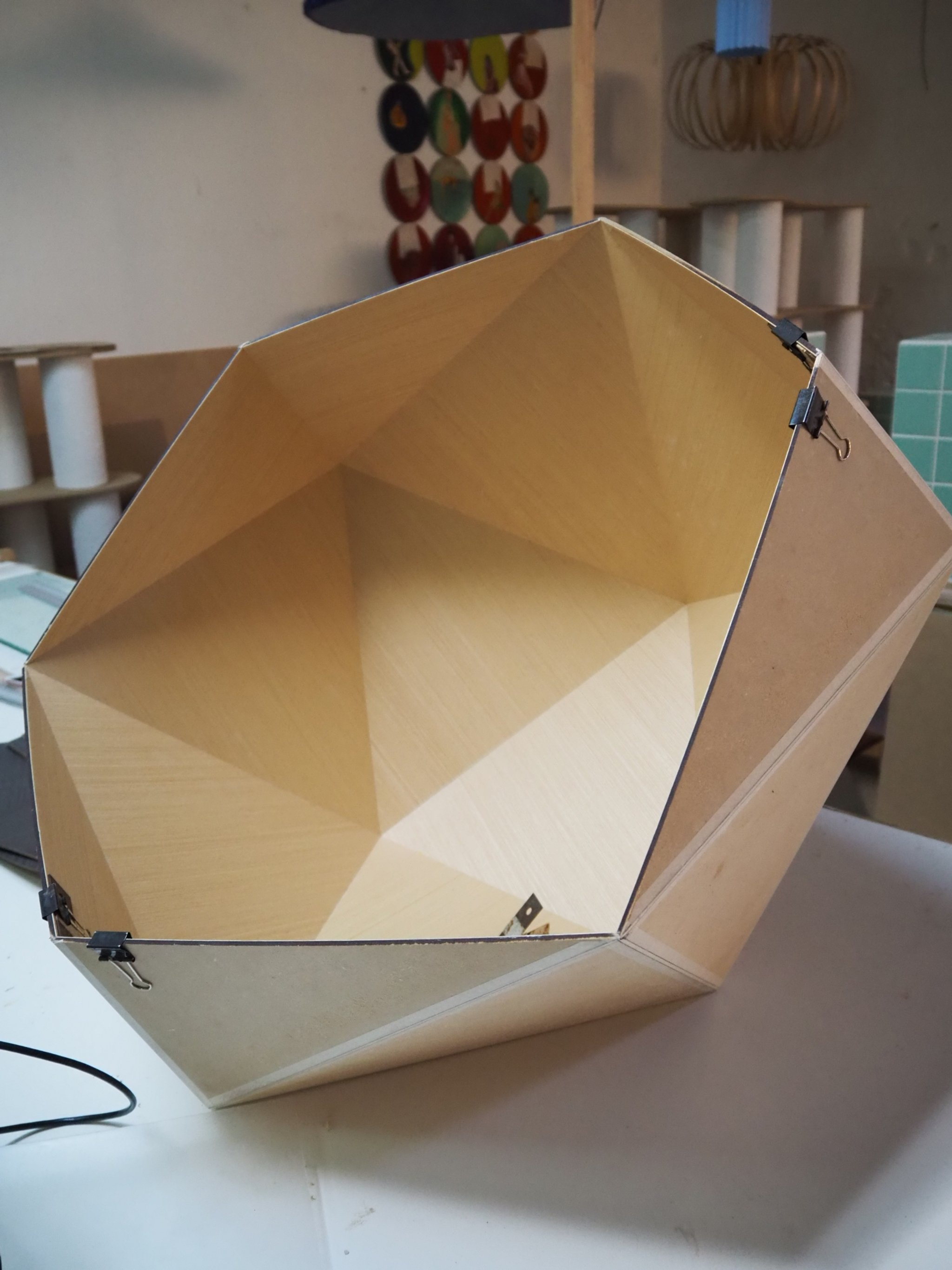 A wooden hexagonal container with an open top, placed on a white surface.