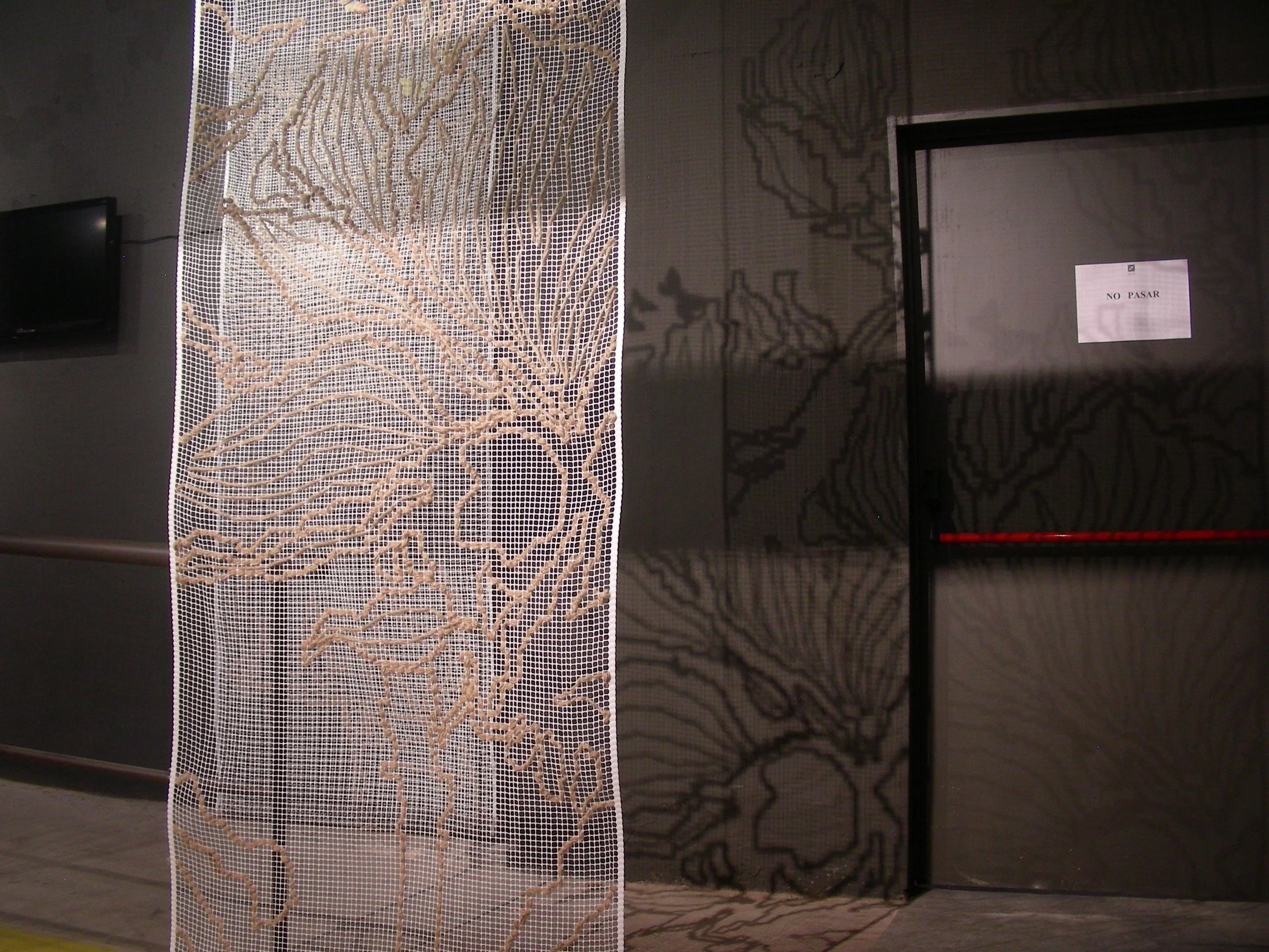 Decorative partition with a leaf pattern next to a door with a sign that says 'No Pasar' in Spanish.