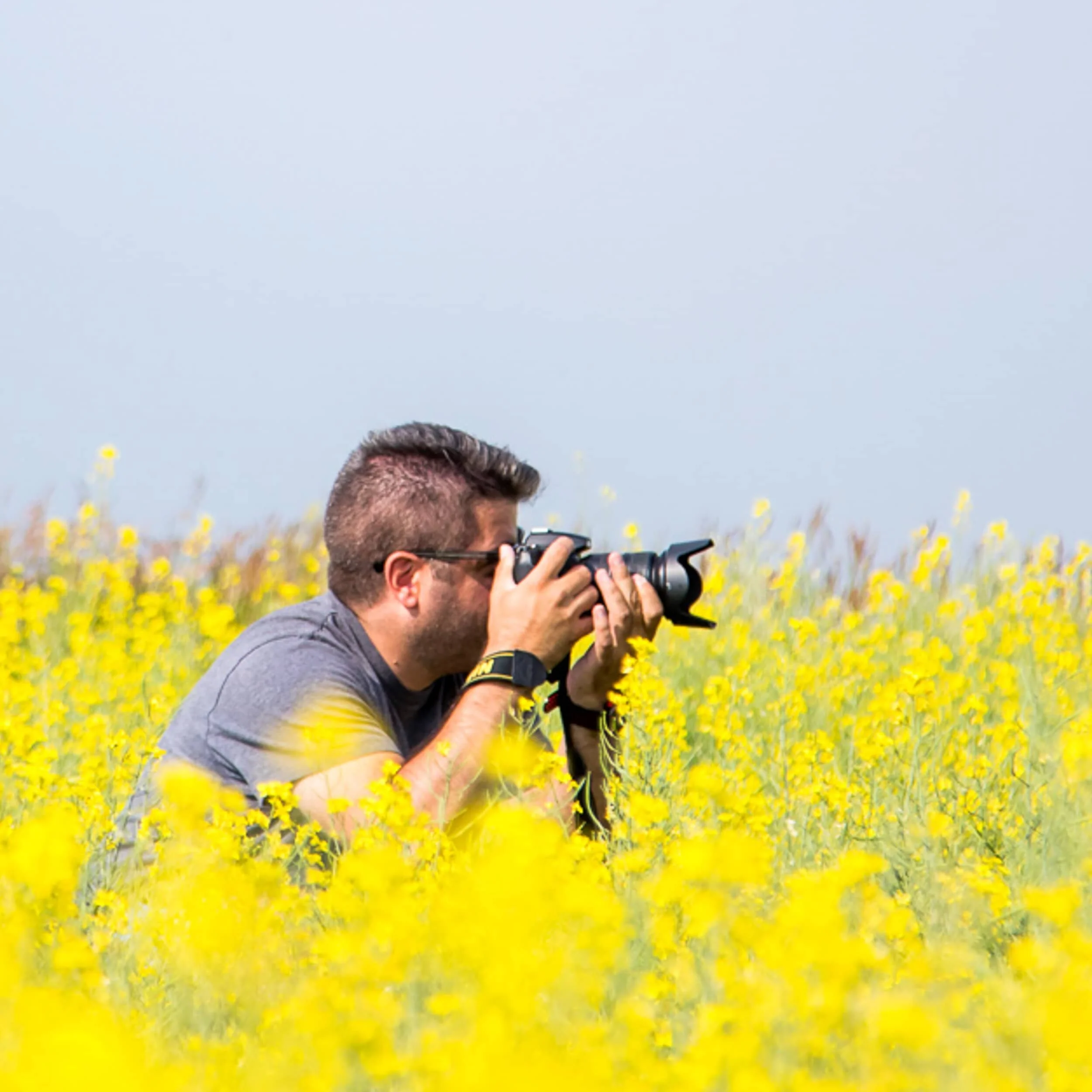 Side-view of me, Bruno Doddoli, crouched in a canola field.