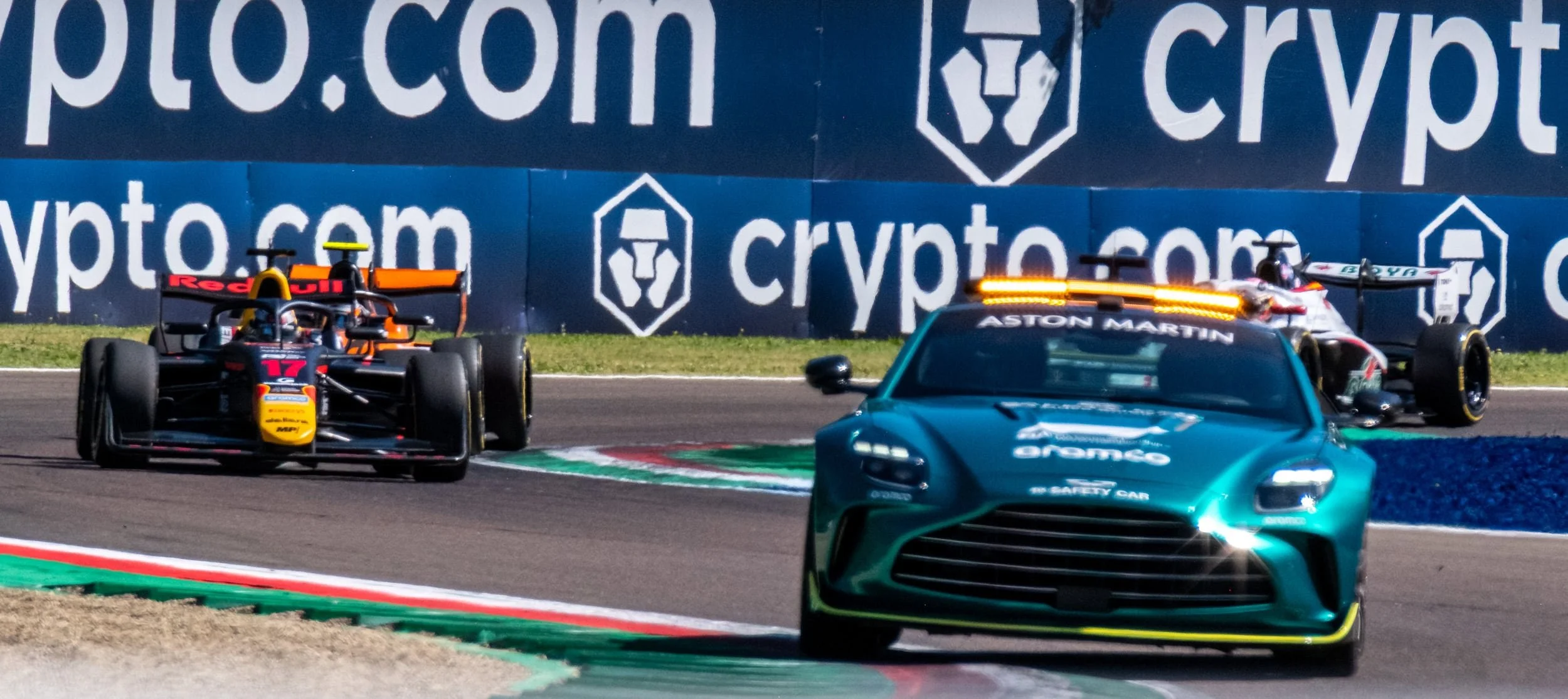 F1 race cars on a track with a blue banner that says 'crypto.com' in the background.
