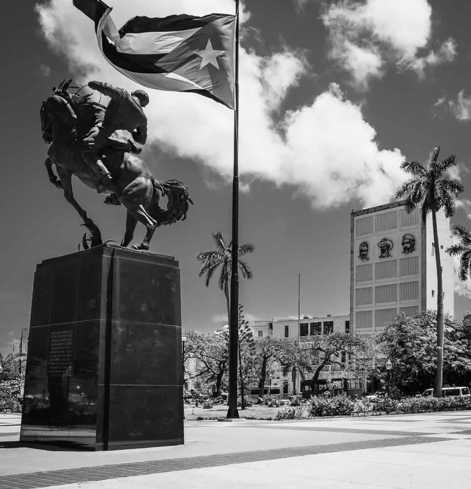 tatue of José Martí in Havana, Cuba, showing the national hero standing tall in a public square with surrounding buildings and trees.