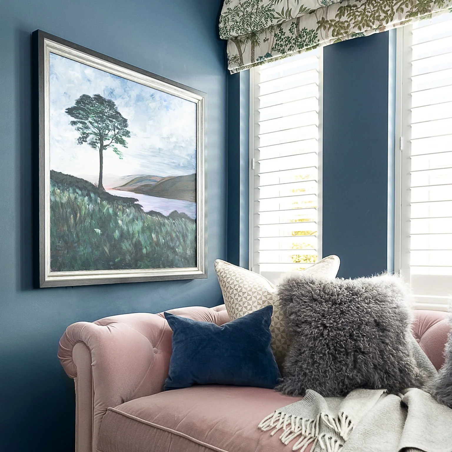Deep blue living room with a soft pink velvet sofa, botanical Roman blind and statement artwork, designed by Holly Scott Interior Design in Oxfordshire.