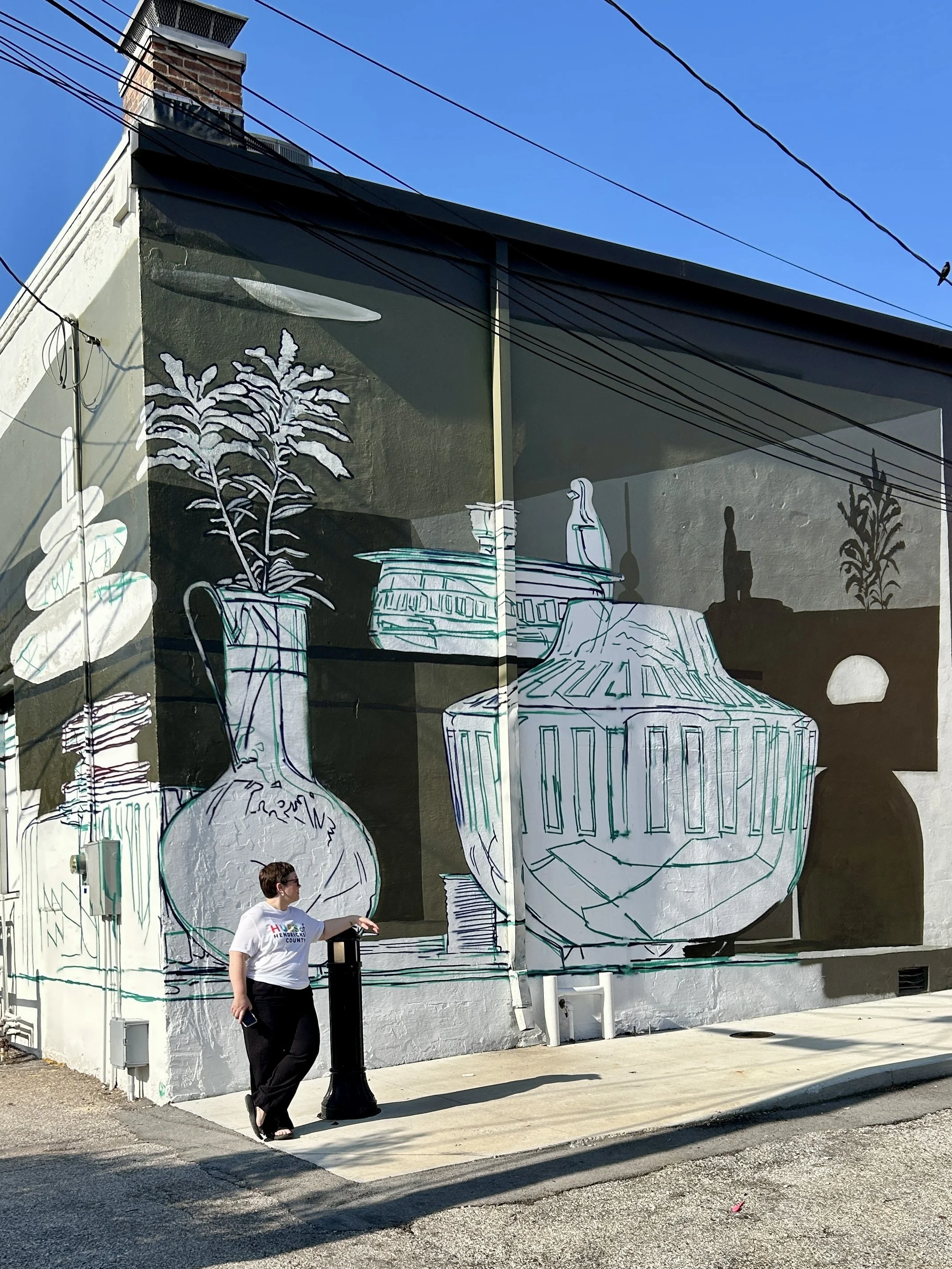 Hues of Hendricks County volunteer posing in front of an unfinished mural