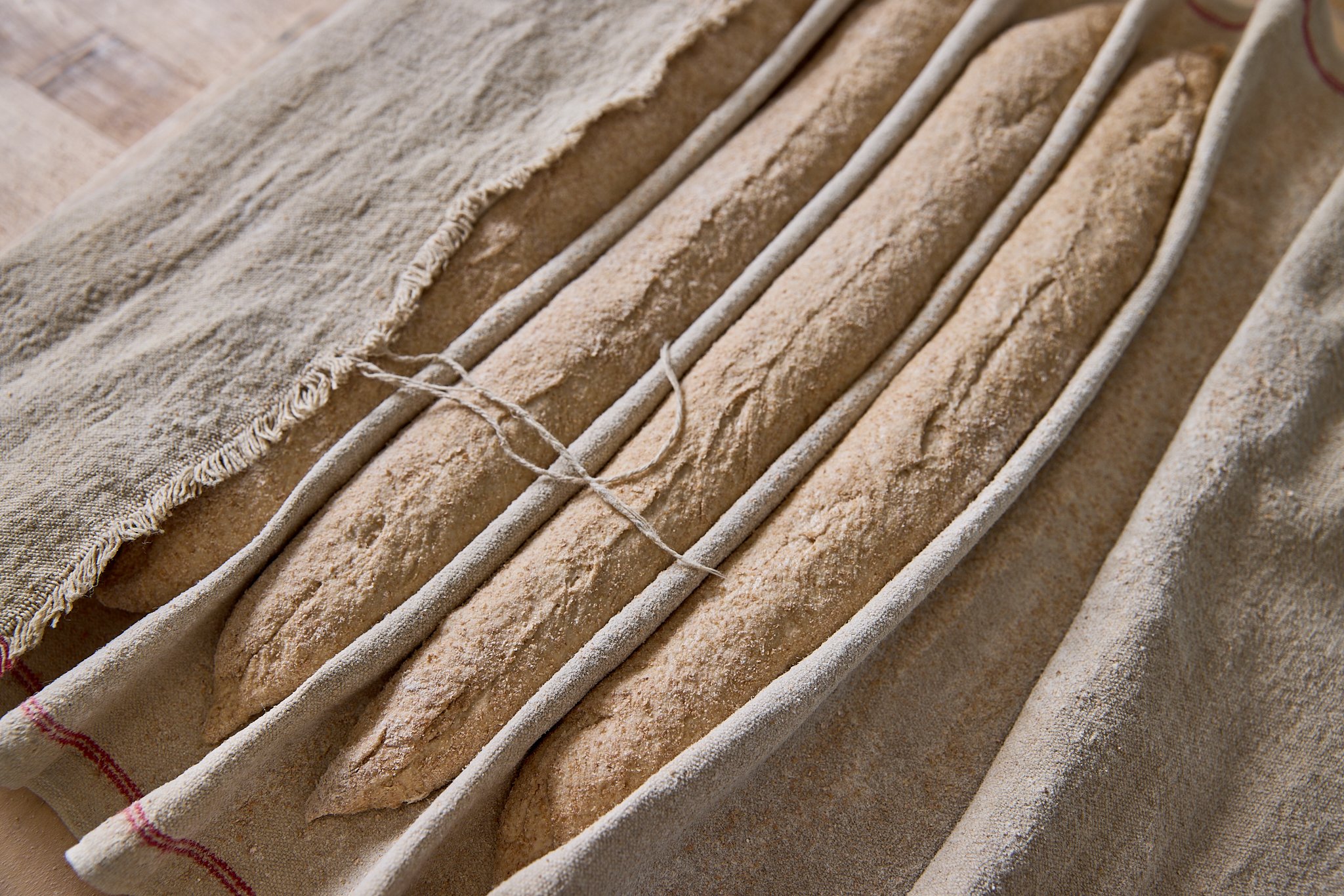 Unbaked baguettes covered with flour on a floured towel and linen cloth.