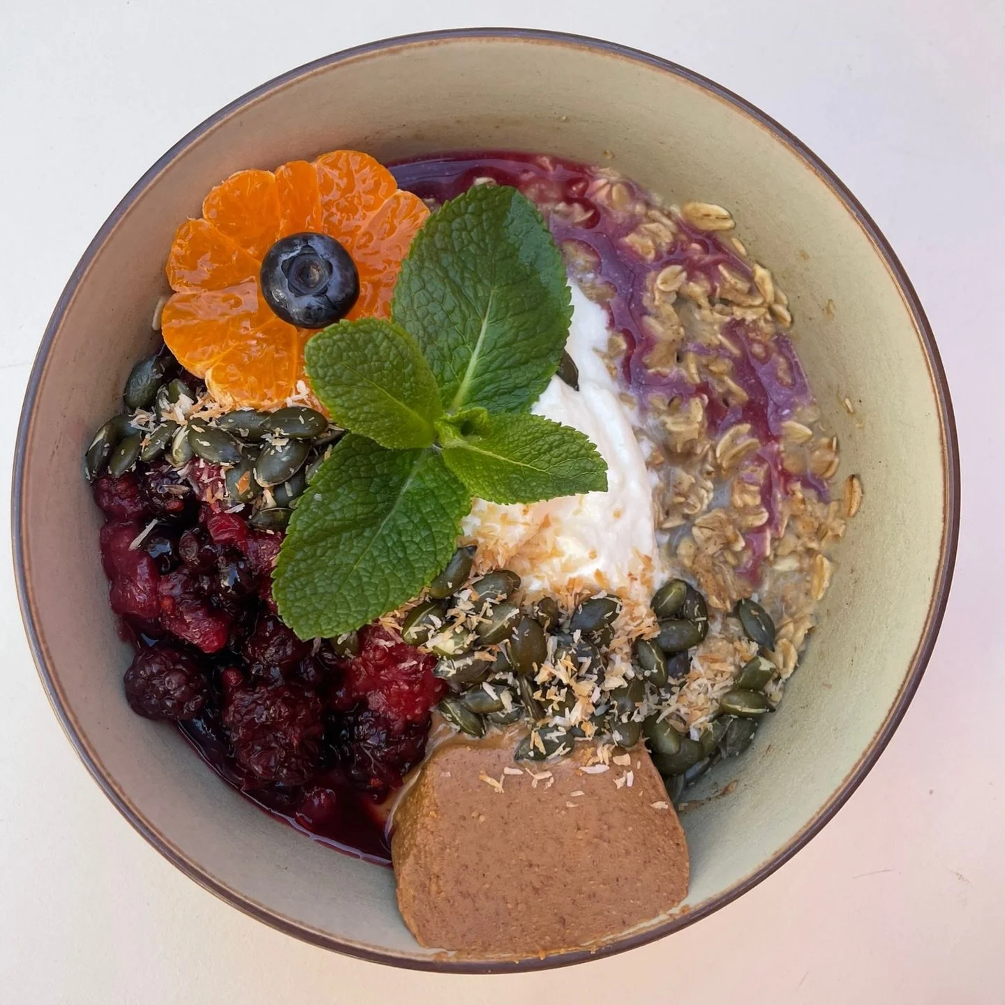Oatmeal bowl with smashed banana, peanut butter, compote, berries, coconut and pumpkin seeds 🫐🍓🥜