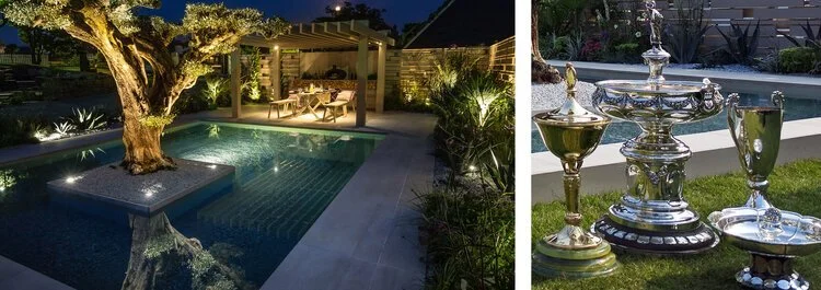 A backyard at night with a small illuminated pool, a large tree, and a covered patio with seating on the left. On the right, a garden scene with an ornate silver fountain and decorative cups/jugs on the grass.