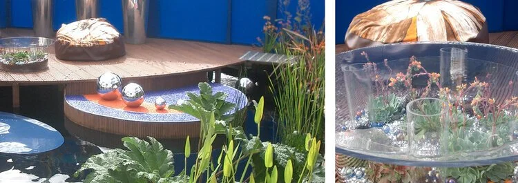 Outdoor patio with a wooden deck, plants, water floating decorations, and a glass table with a parasol.