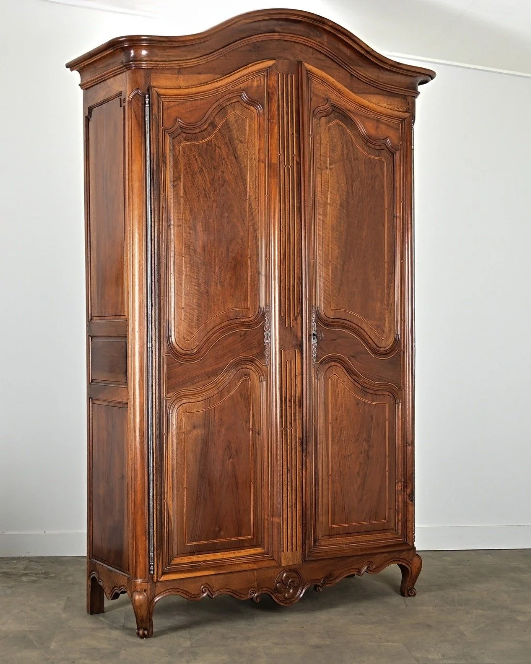 Provincial French 18th Century Louis XV Solid Walnut &amp; Inlay Armoire stuns with every detail! From the bonnet-top crown &amp; exquisite pinstripe inlay to the escargot-style feet. A monumental piece of craftsmanship, complete with ironwork, key l