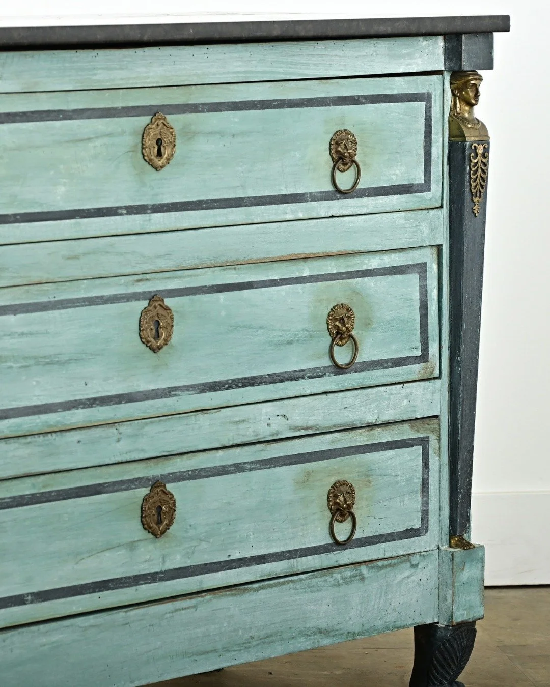 French 19th Century Empire Painted Commode with three-drawers sporting its original black fossil marble top. Recently updated in a Caribbean-blue painted finish complementing the gilt bronze accents, including a pair of gilt bronze caryatid busts ove
