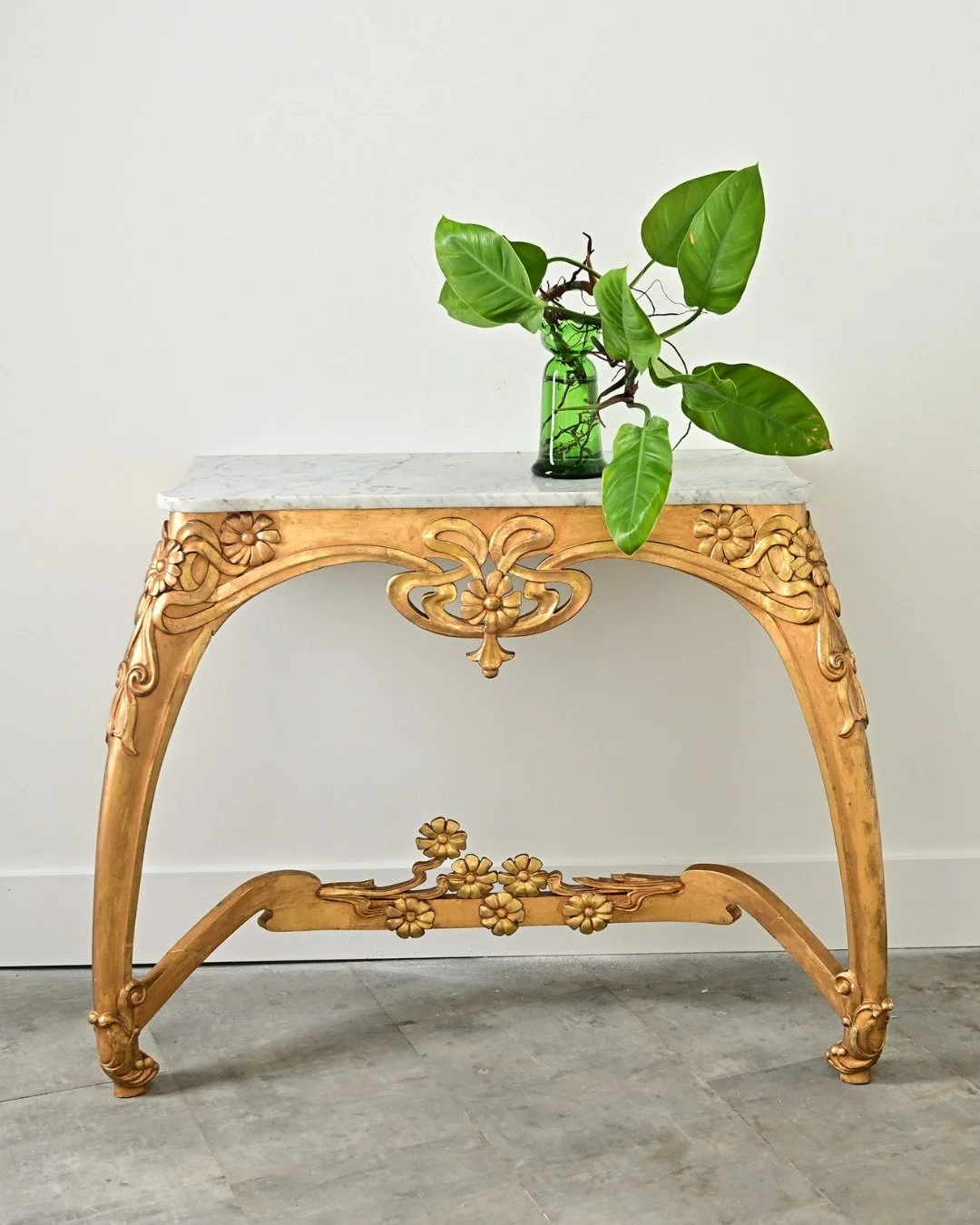 French Art Nouveau Gilt Console Table, circa 1900, a sculptural piece that expresses the artistry of the period. Shaped white marble top is slightly lobed at the front corners flowing in line with the gently arching splay of the two legs entangled in