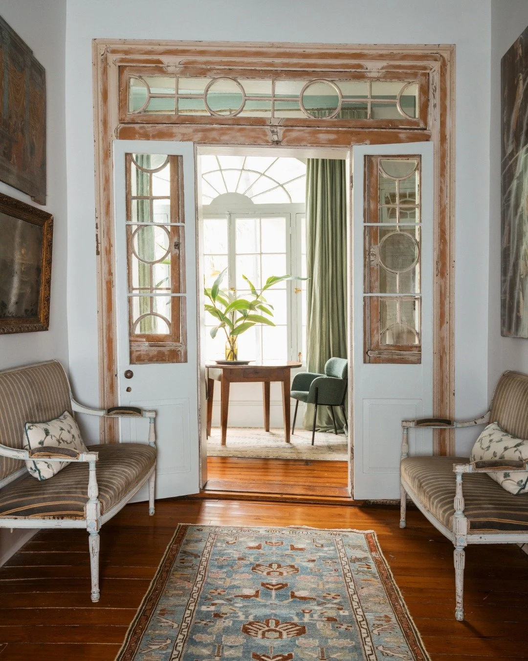 The hallway between a salon &amp; sunroom bathed in natural light from the courtyard of a French Quarter pied-&agrave;-terre is a reminder that even secondary spaces deserve attention, with a collection of antique furniture &amp; accessories to add s