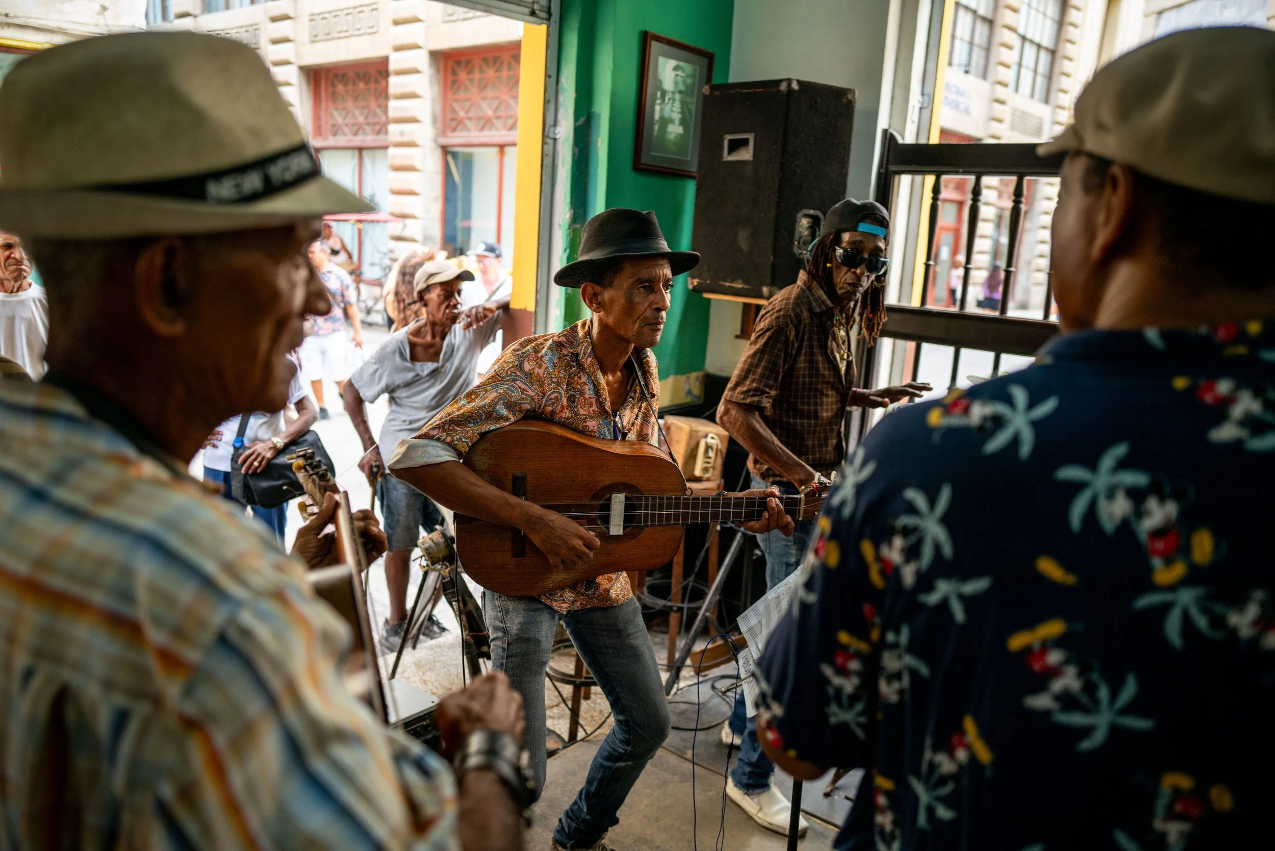 Musicians playing instruments during a street performance with an audience nearby.