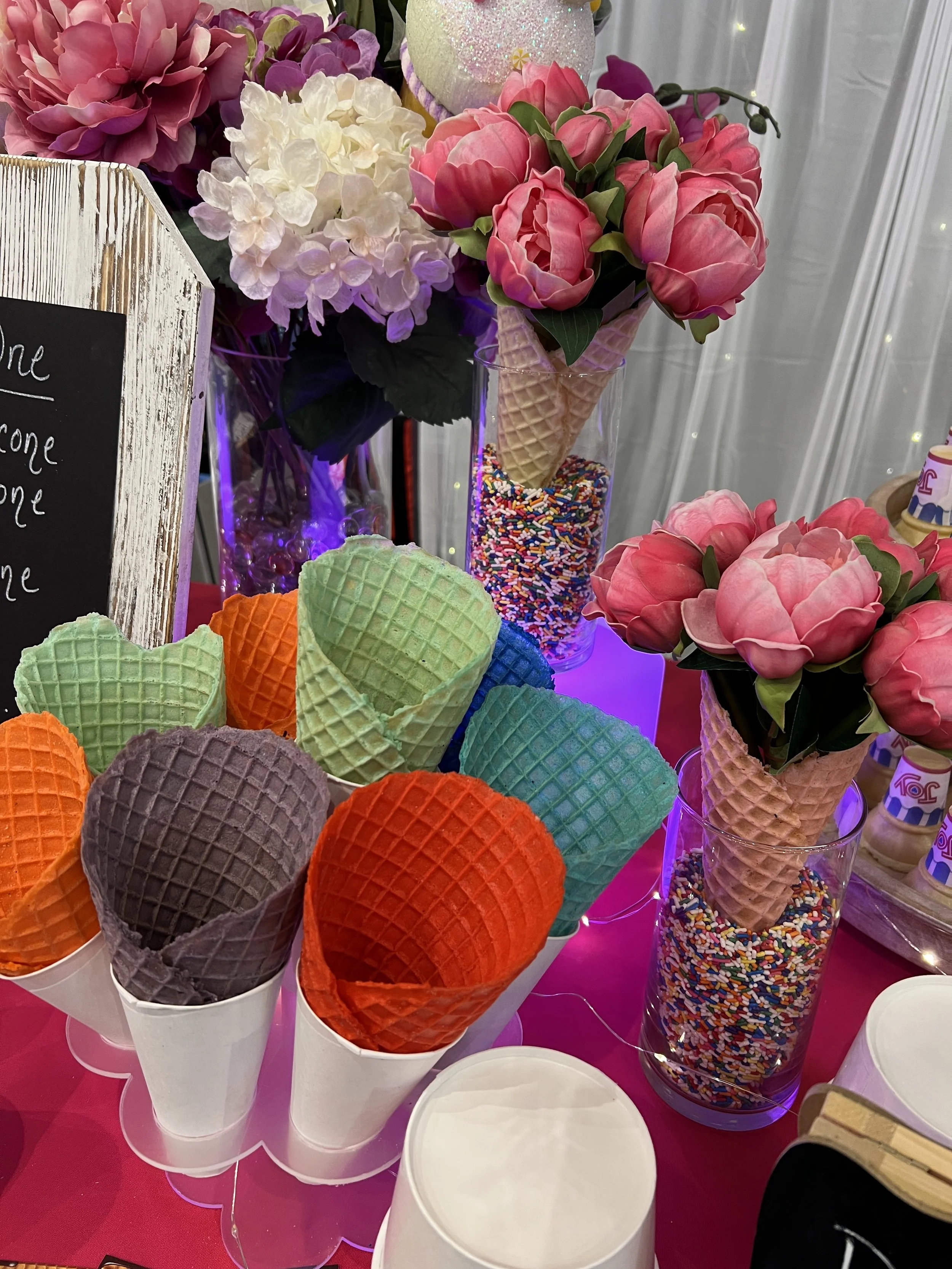 Arrangement of colorful ice cream cones and flowers in the image.