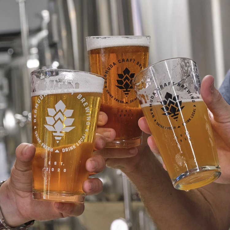 Three people clinking glasses of beer in a brewery.