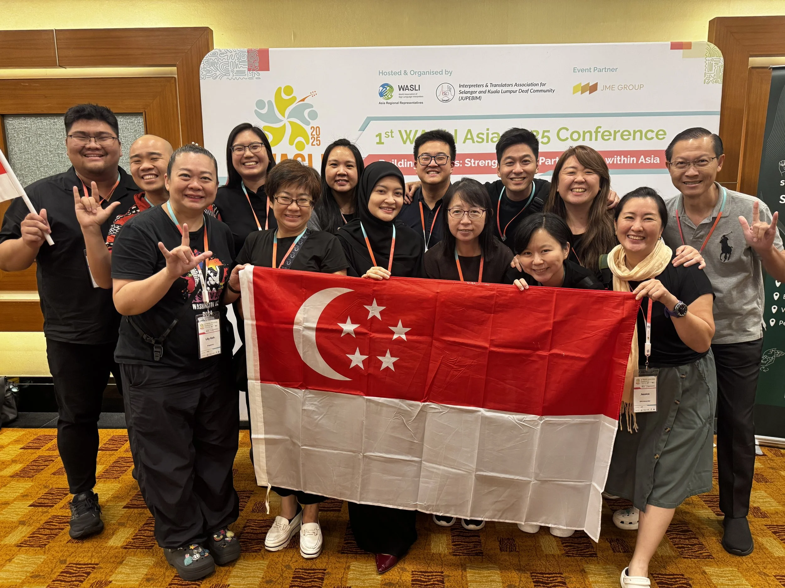 Group of people standing in front of a backdrop holding a Singapore flag.