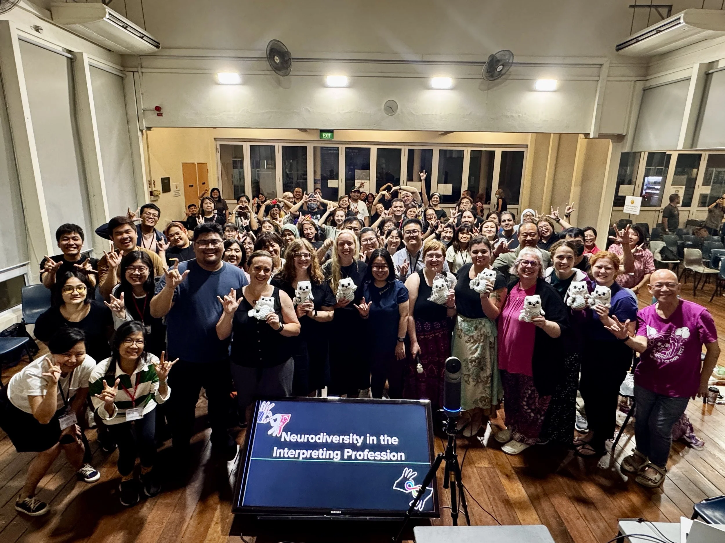 Large crowd of people gathered in an auditorium in front of a screen.