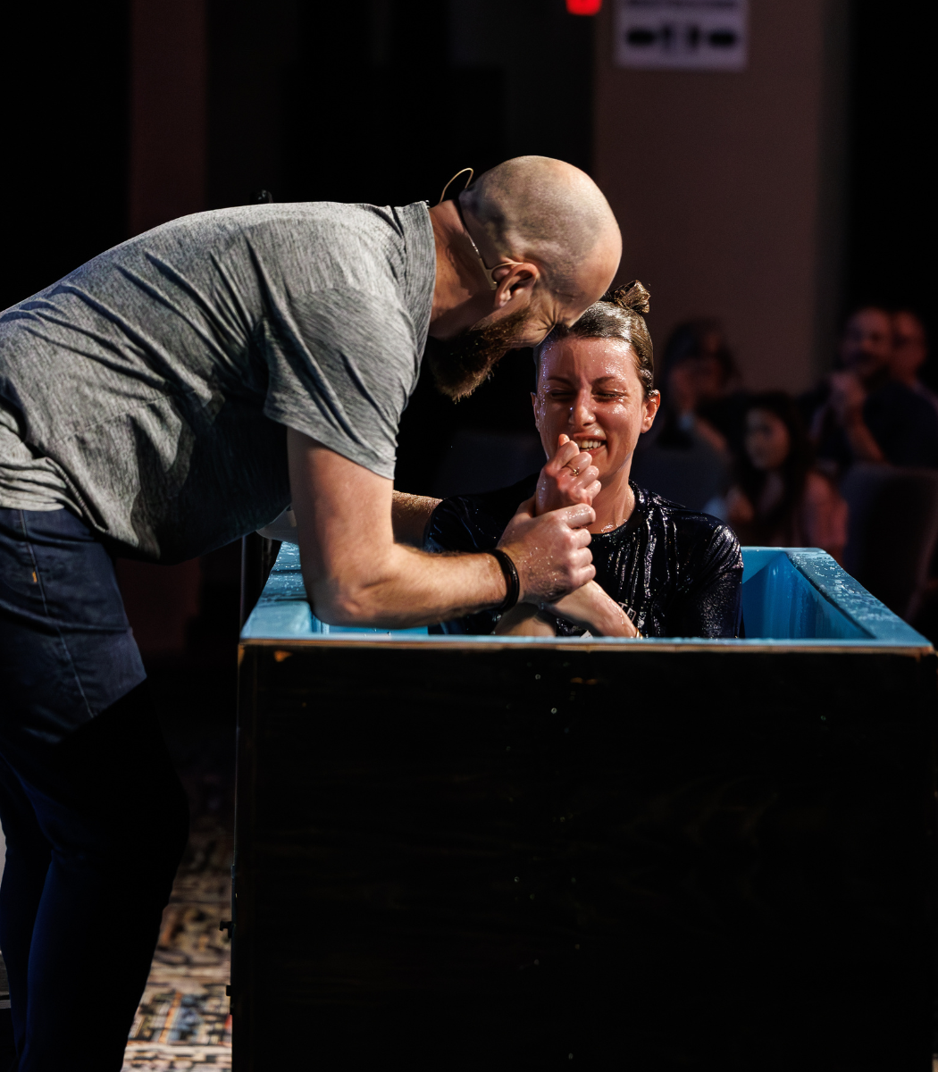 A man baptizing a woman in a baptismal pool.