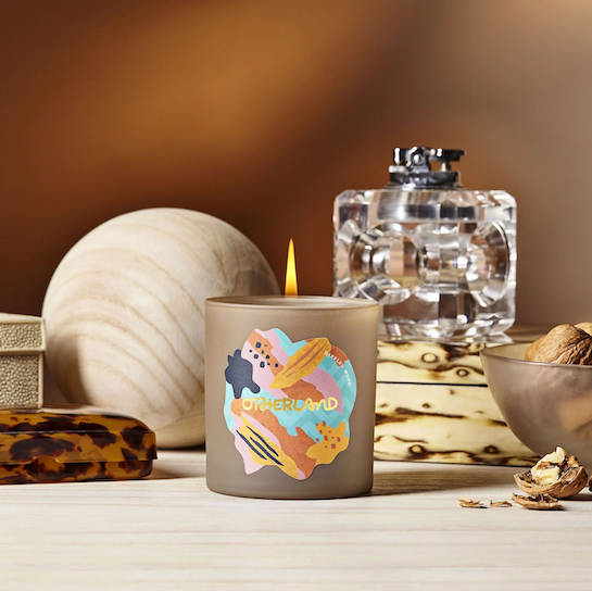 Lit candle in frosted glass, surrounded by warm-toned decor and natural elements