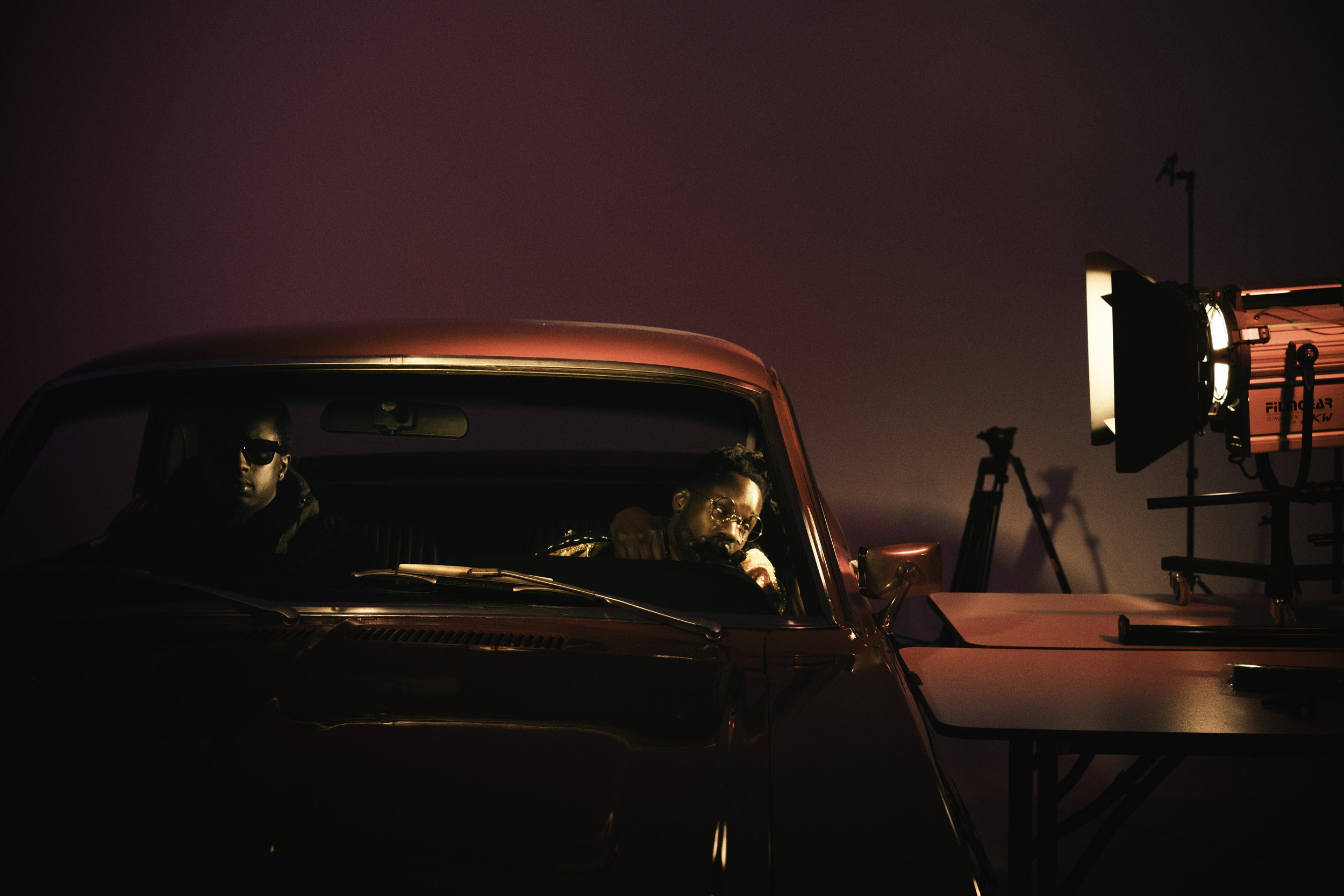 Deux personnes dans une voiture sombre avec un éclairage dramatique, une grande lumière à droite, studio de photographie.