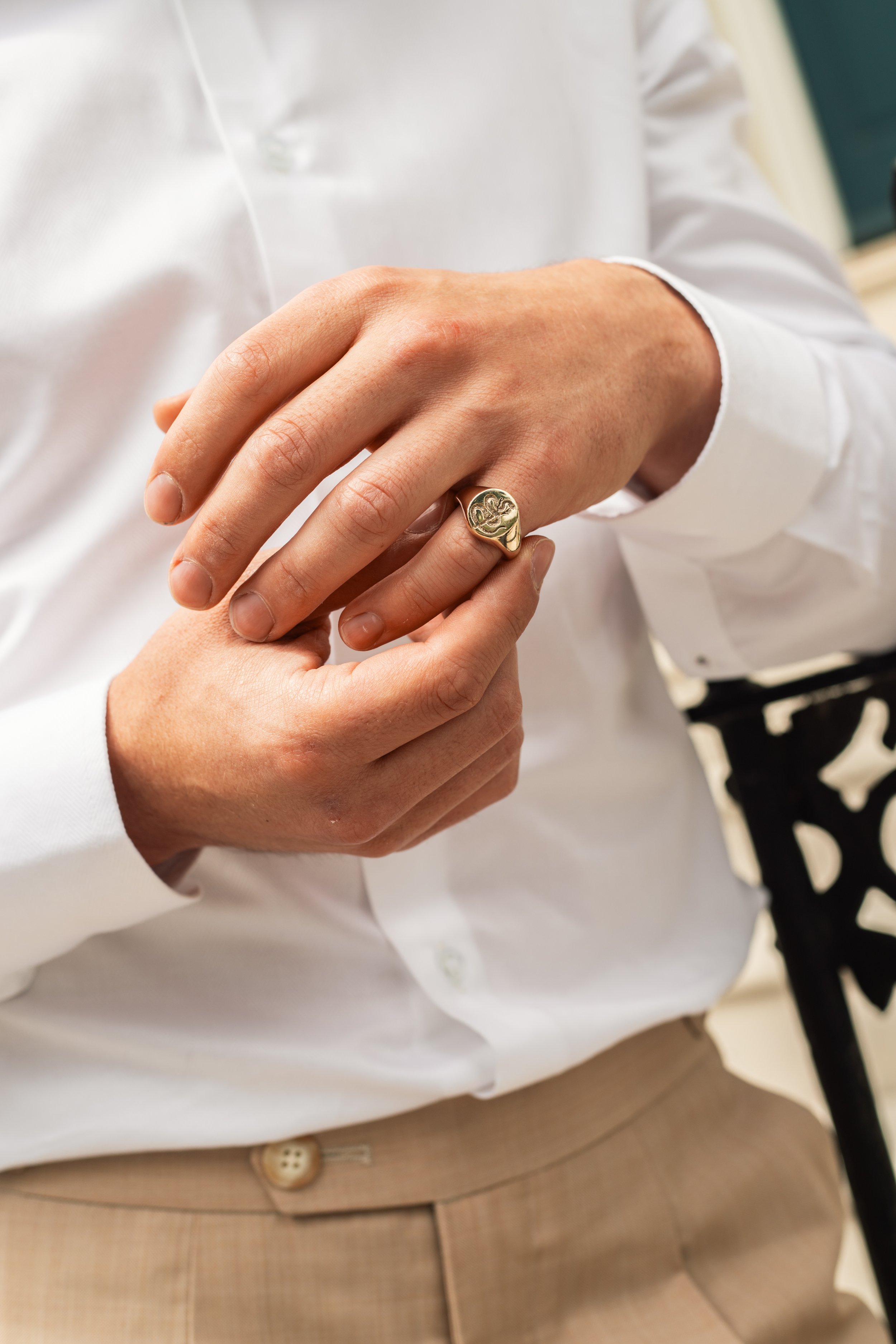 A gentleman's hand wearing a solid gold signet ring.