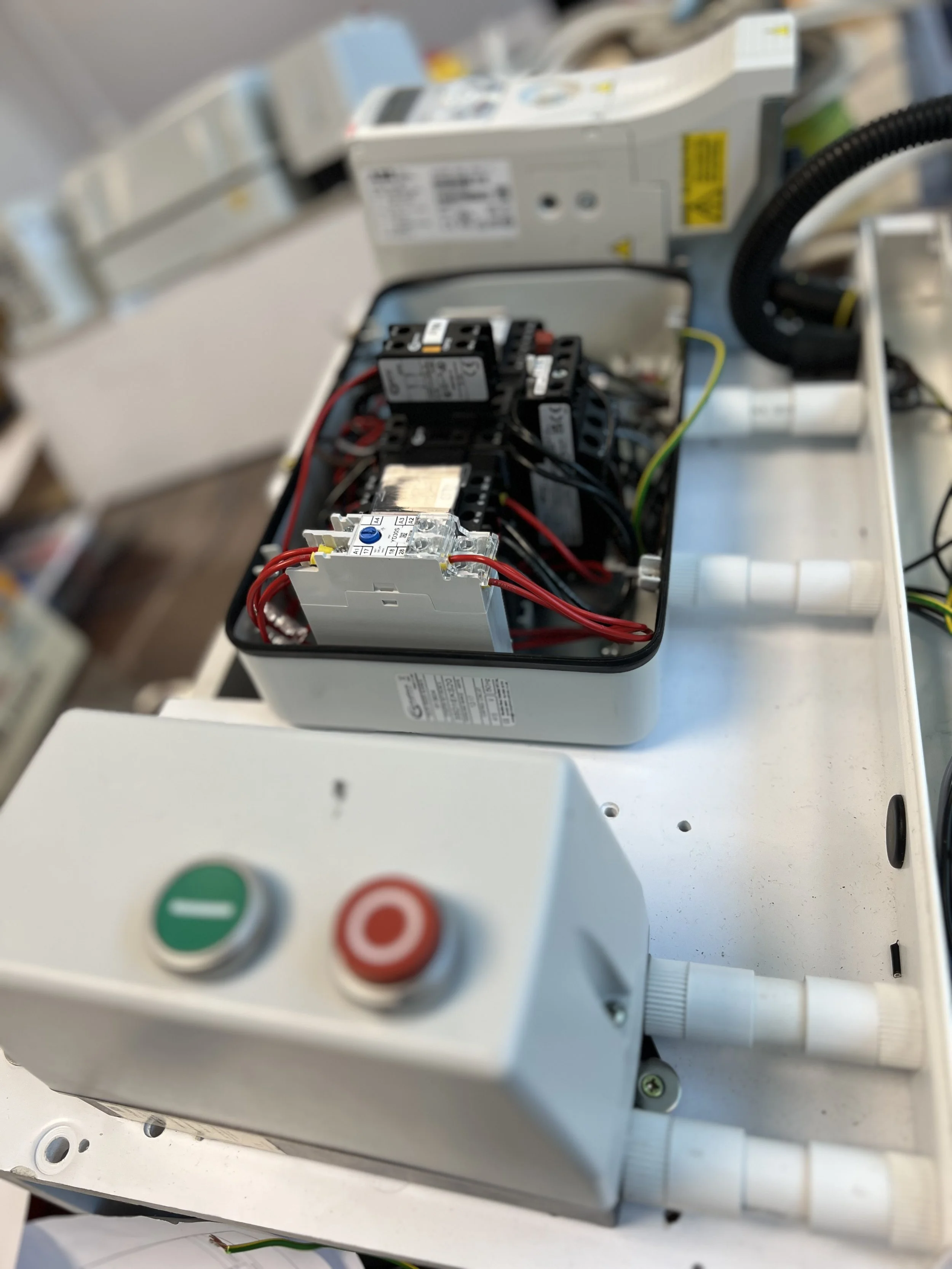 Open electrical control box with wiring and circuit components inside, on a white work surface.