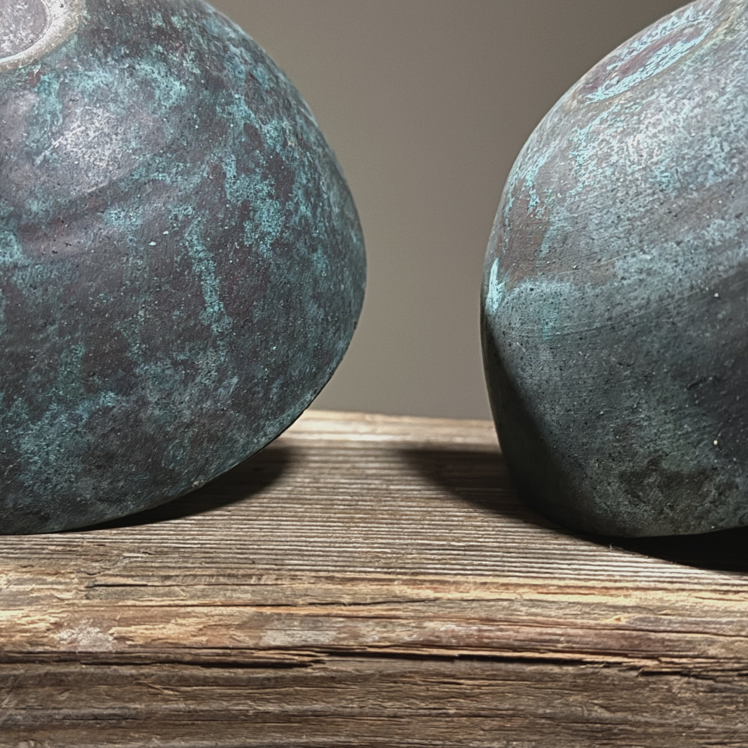 Close-up of textured surface on one Brutalist candle holder showing layered blue-green patina.