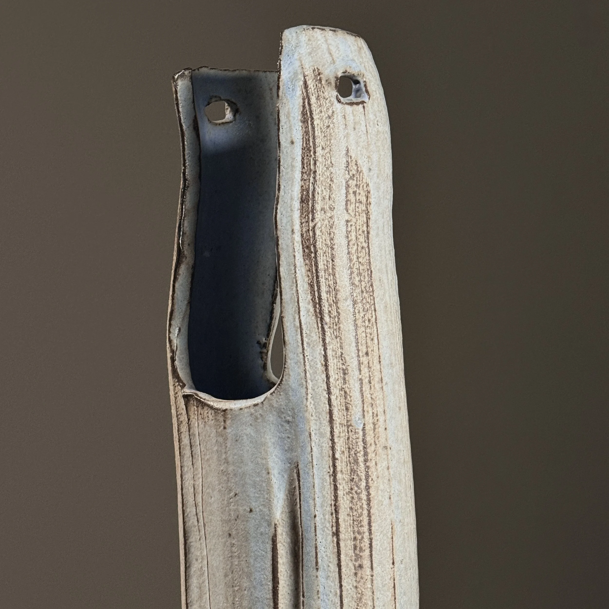 Close-up detail of wood-fired surface effects including pale blue streaks and speckled grey markings