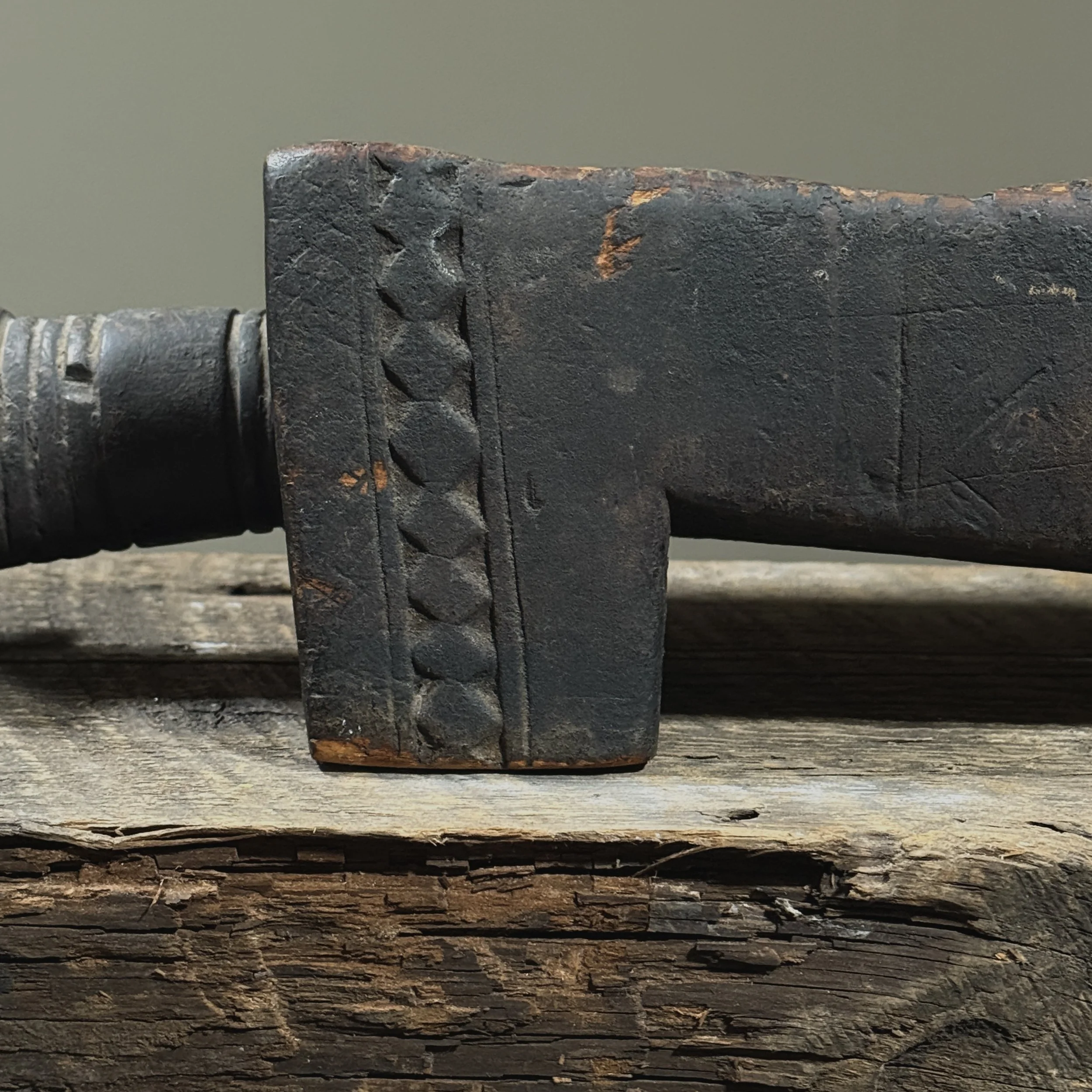 Close-up of geometric carving on side of antique African mancala board