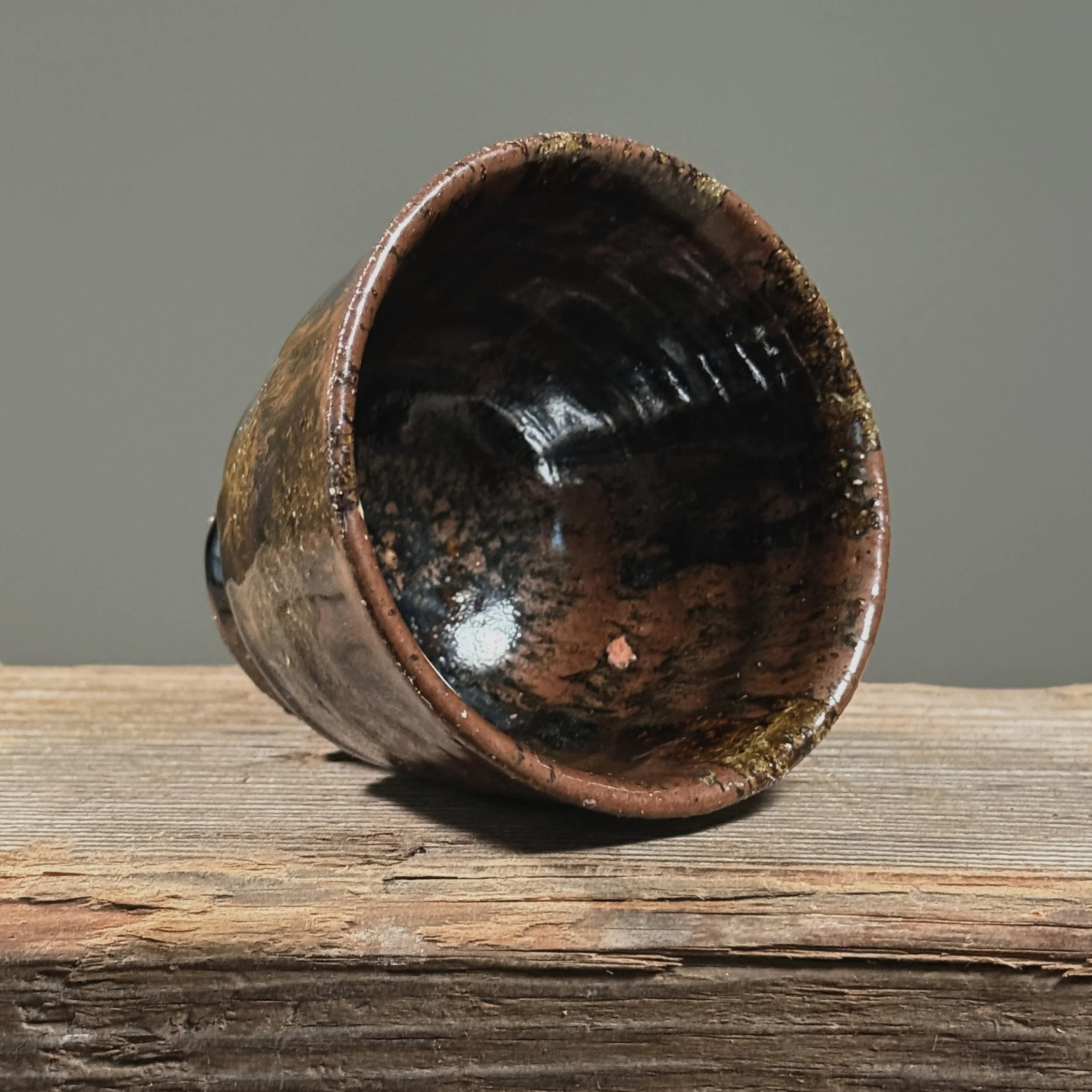 Brown glossy drip yunomi cup. Vertical glaze drips on warm brown stoneware. Unglazed foot ring exposed.