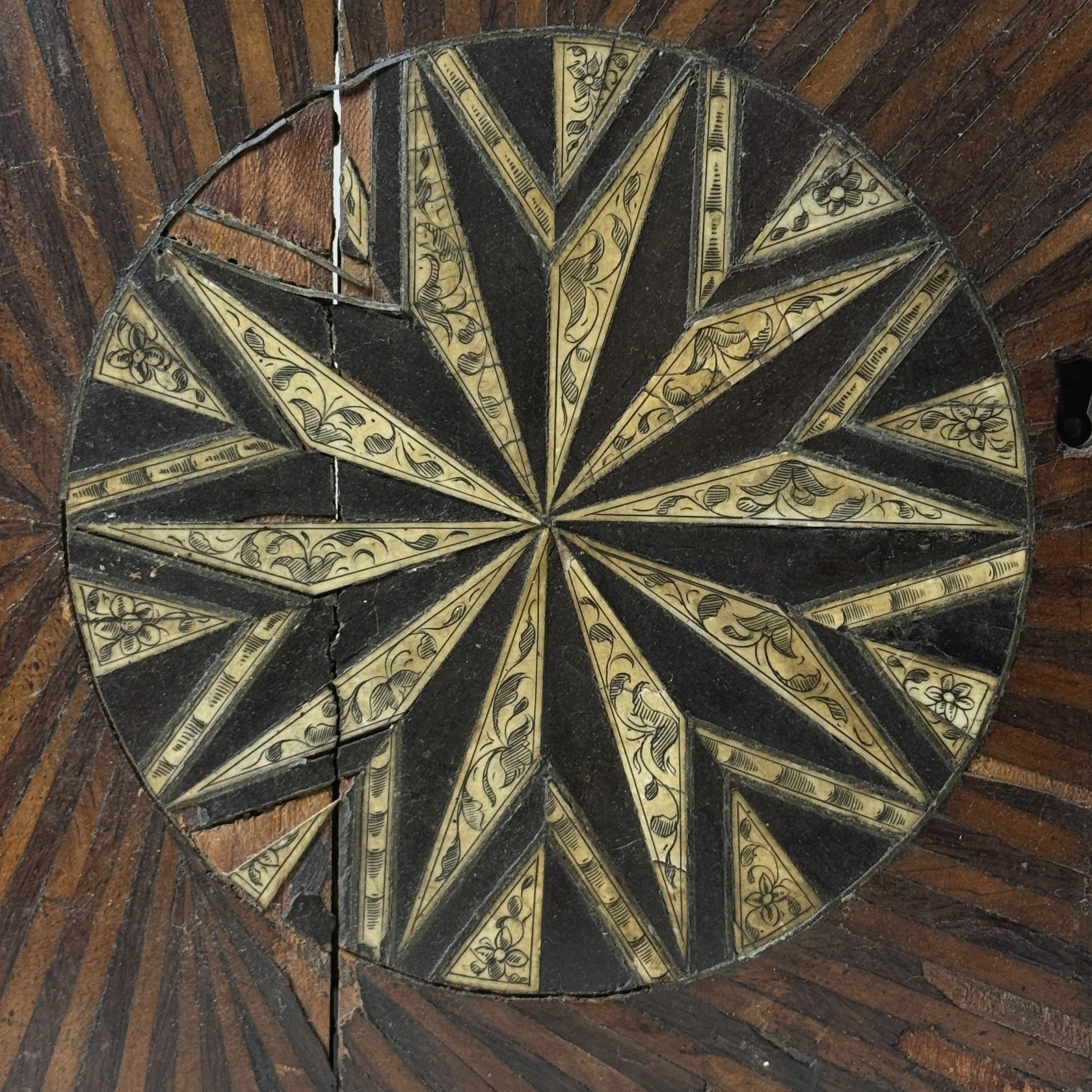 Front view of cabinet doors. Two-tone sunburst parquetry. Hand carved wood.