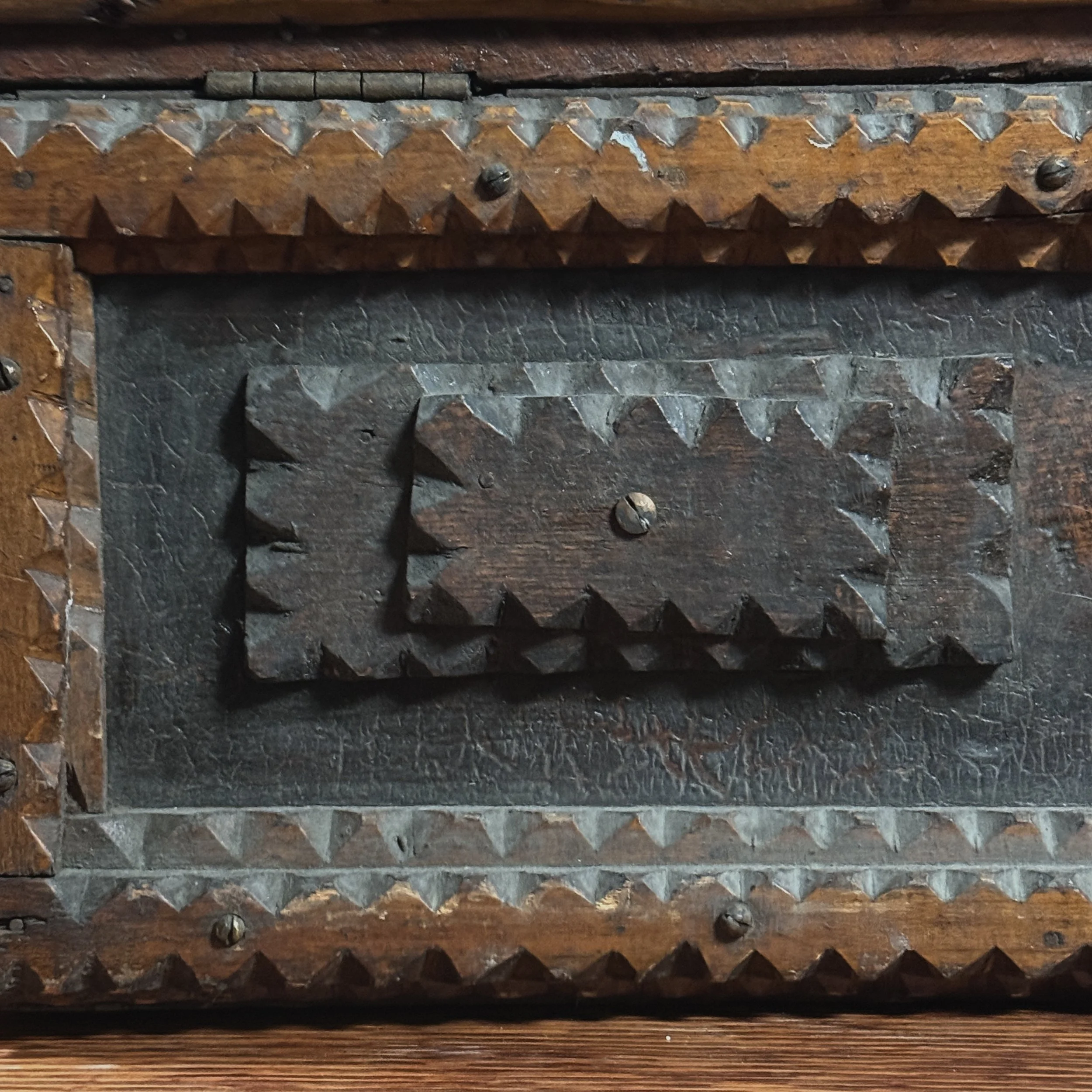 Close-up of the layered wood and notch-carving technique on the chest's edge.
