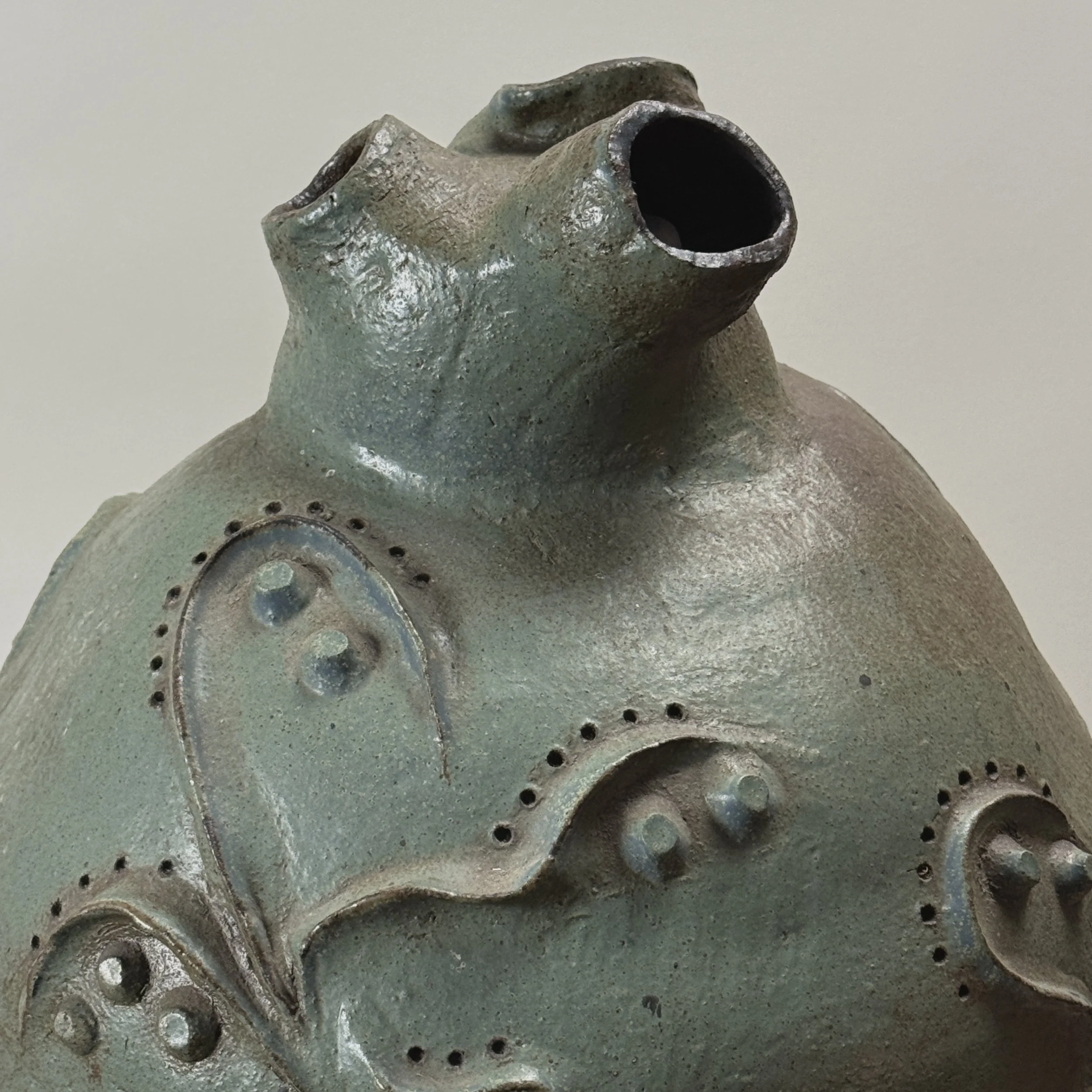 Organic modern ceramic vessel with three openings and textured surface.