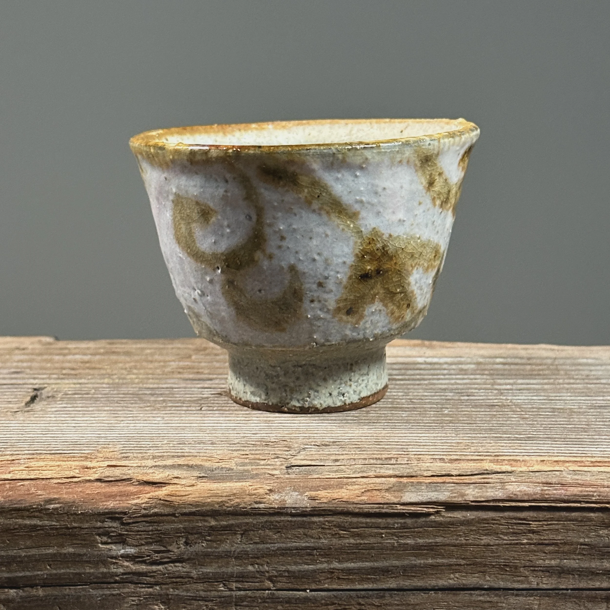 Pale purple-pink yunomi cup. Matte surface. Flourish design painted near rim on exterior wall.