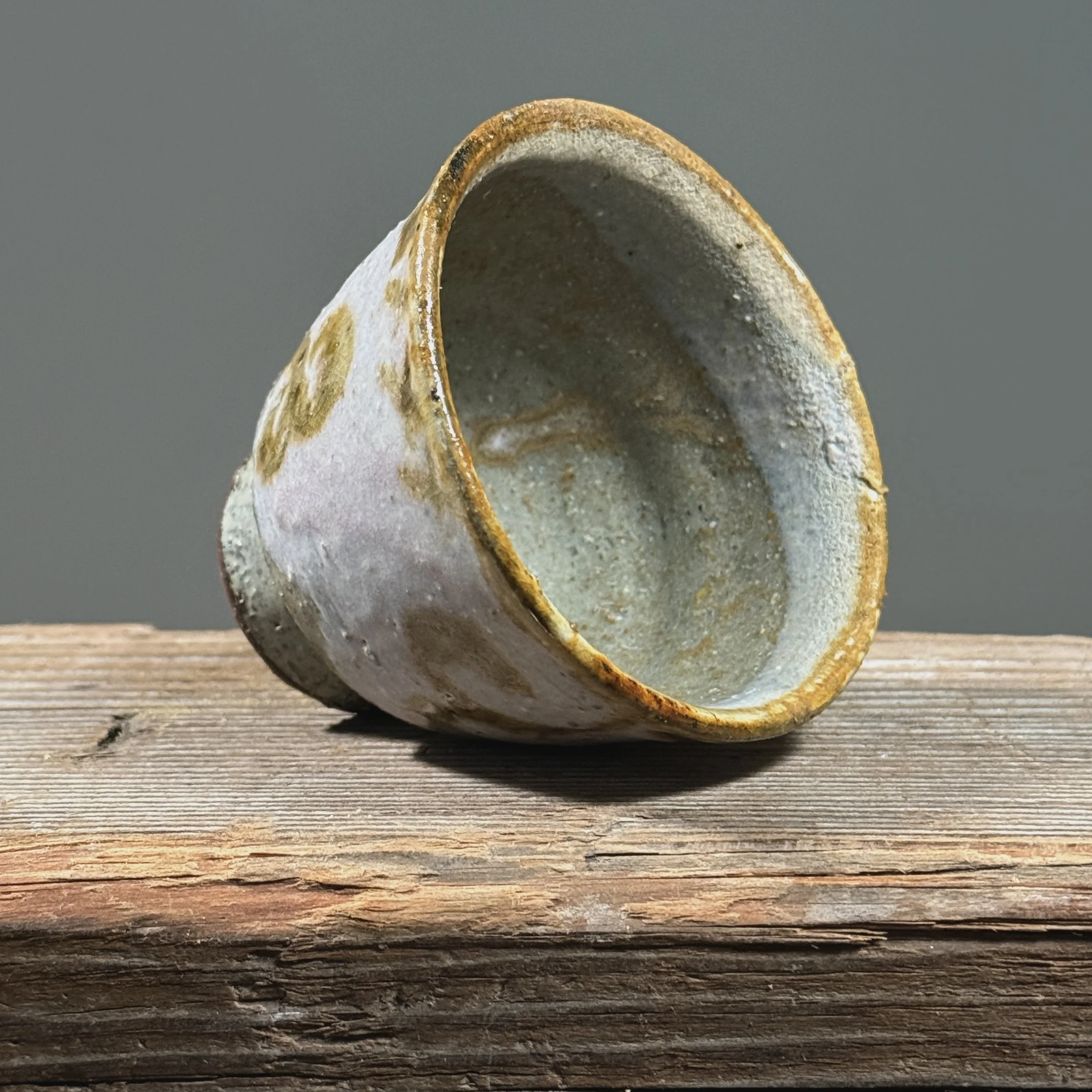 Pale purple-pink yunomi cup. Matte surface. Flourish design painted near rim on exterior wall.